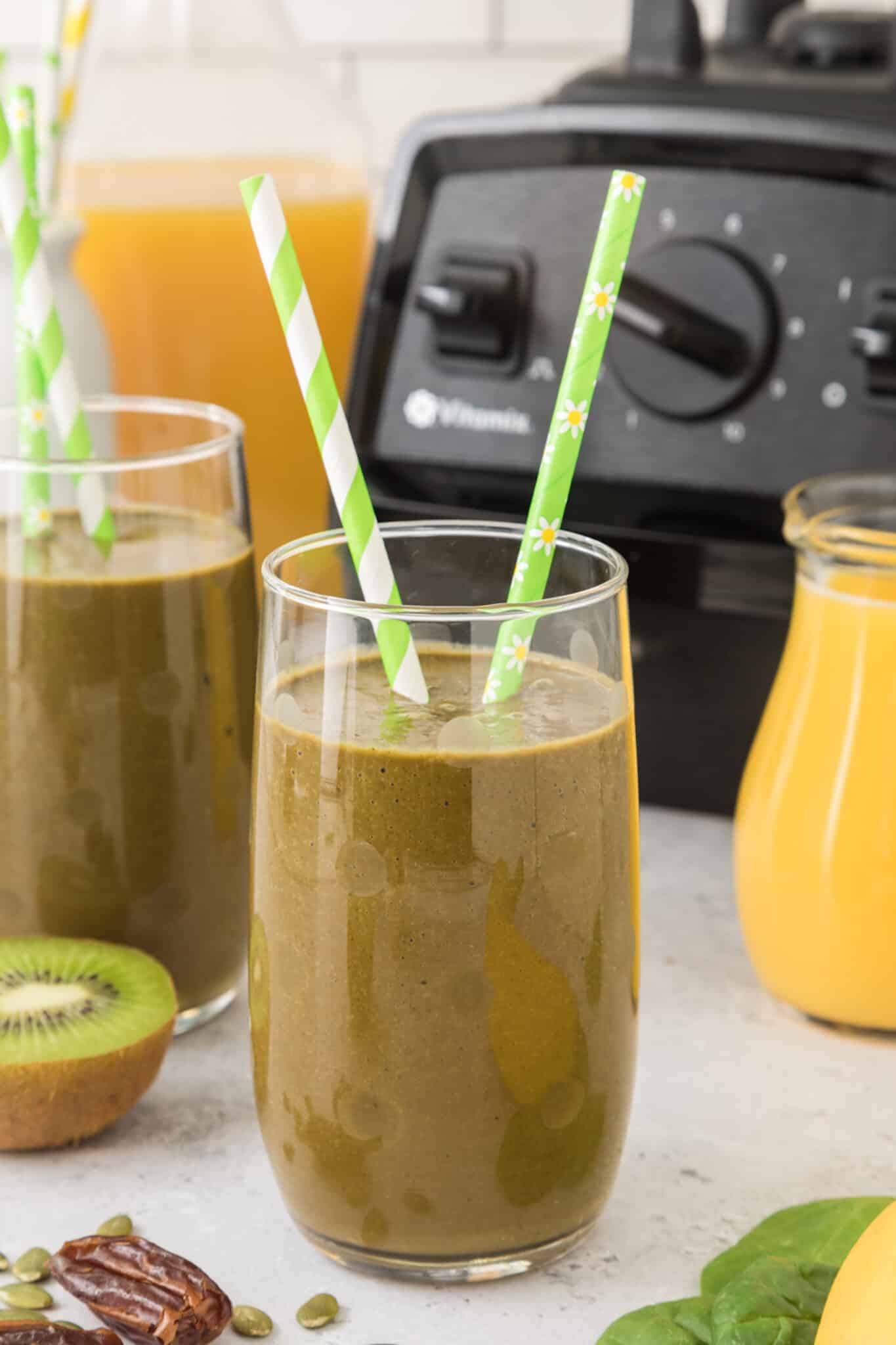 A glass of iron rich green smoothie with two green striped straws.