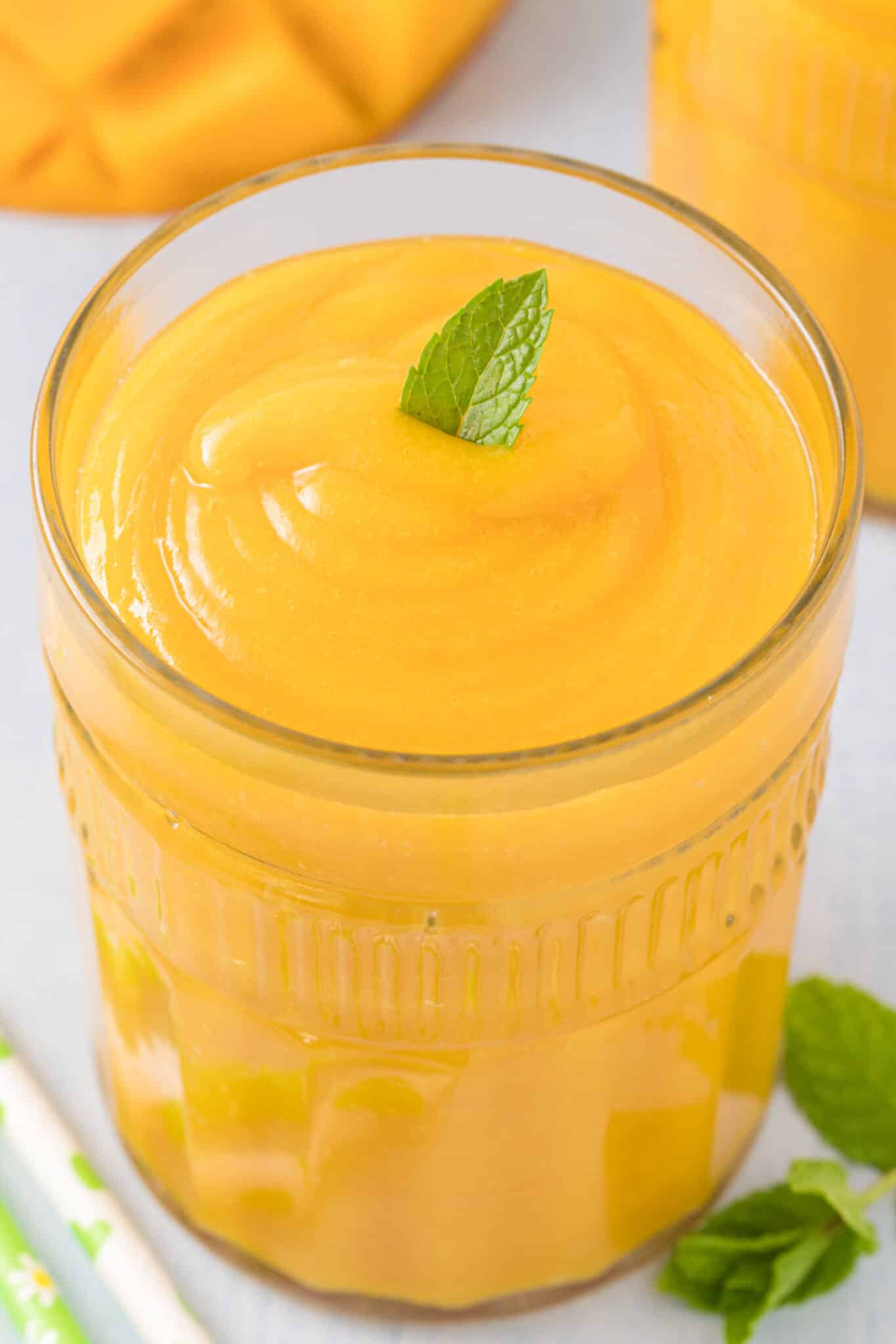 mango juice served in a glass with a fresh mint leaf.