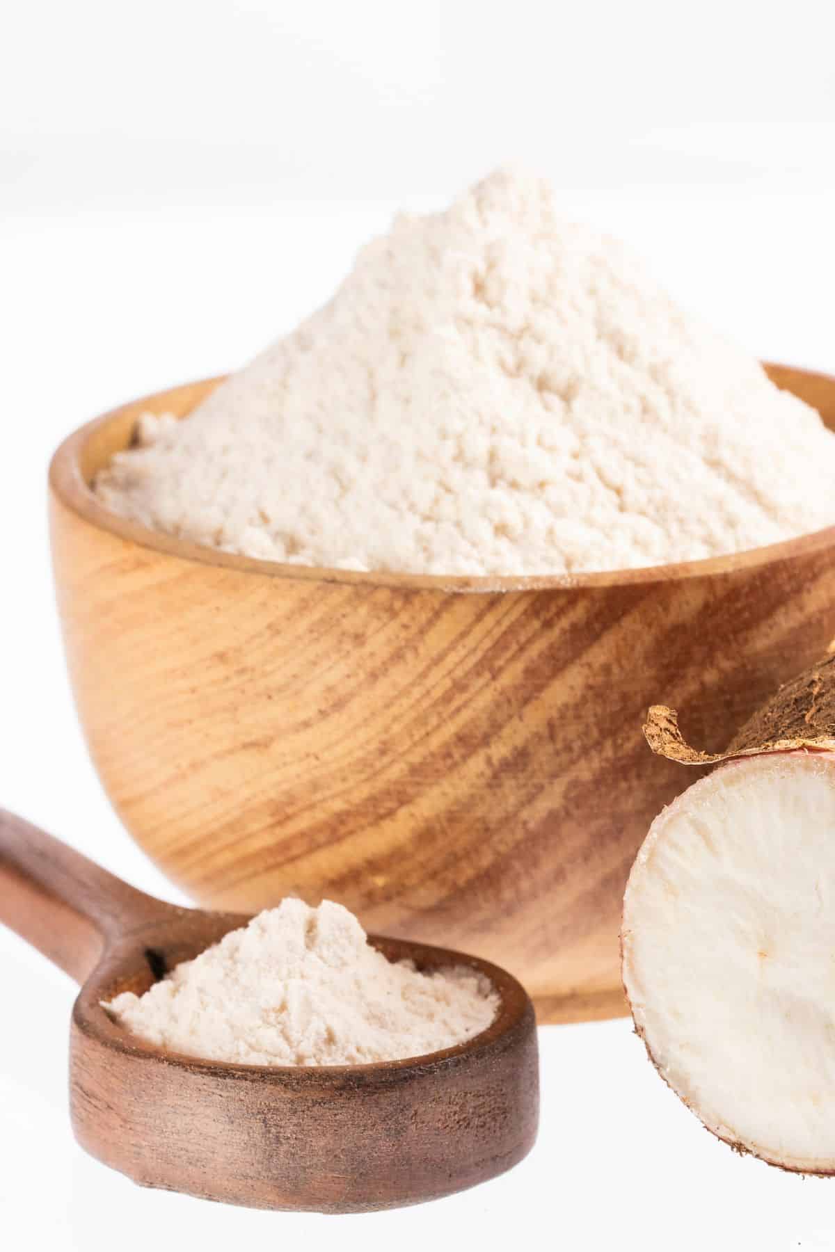 Bowl and spoonful of arrowroot starch with fresh arrowroot.