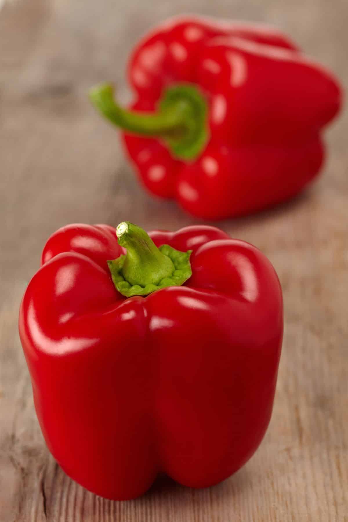 Red bell peppers on wooden surface.