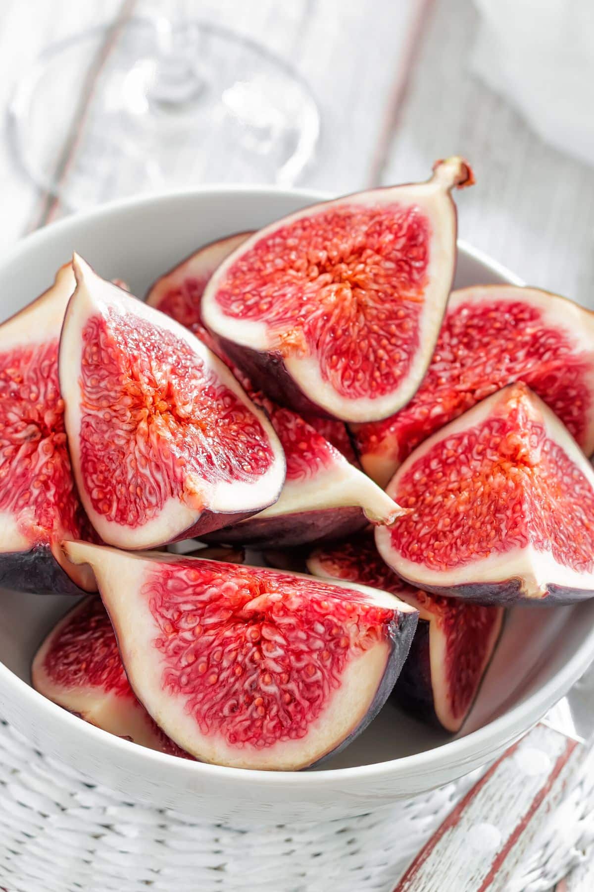 A white bowl of quartered fresh figs.