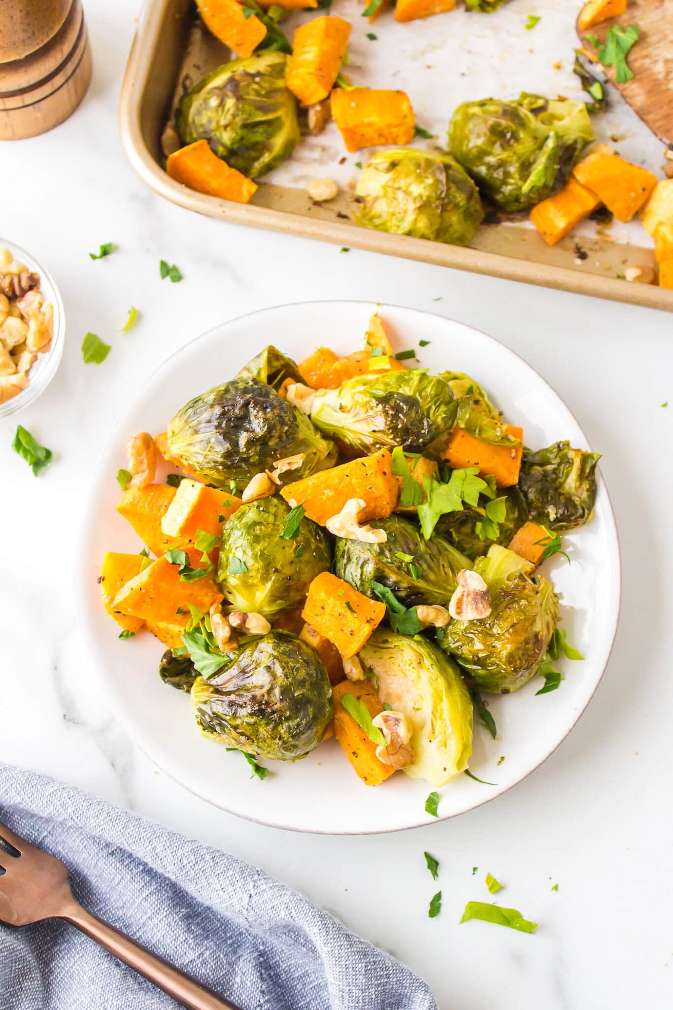 Roasted brussels sprouts and sweet potatoes on a white plate.