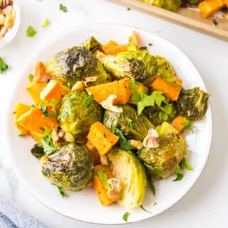 Roasted brussels sprouts and sweet potatoes on a white plate.