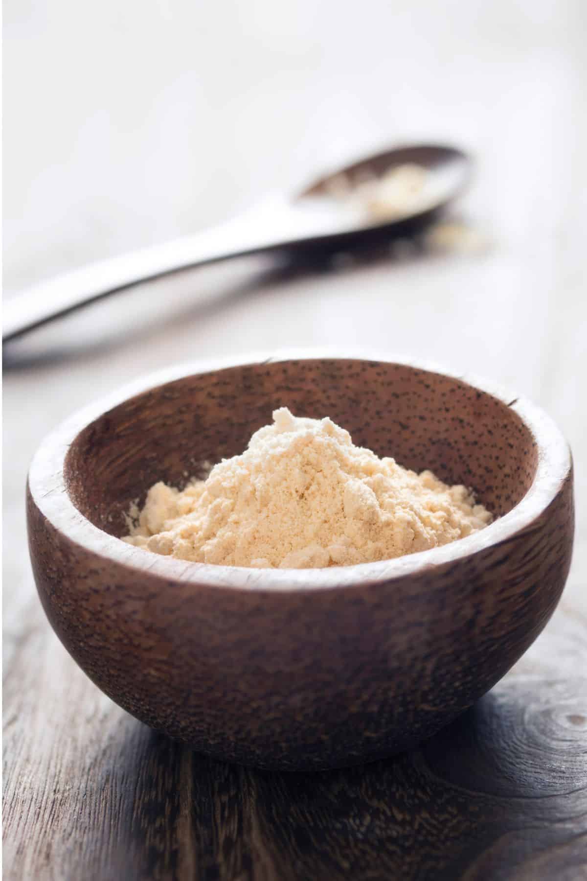 Bowl of chickpea flour on wooden surface.