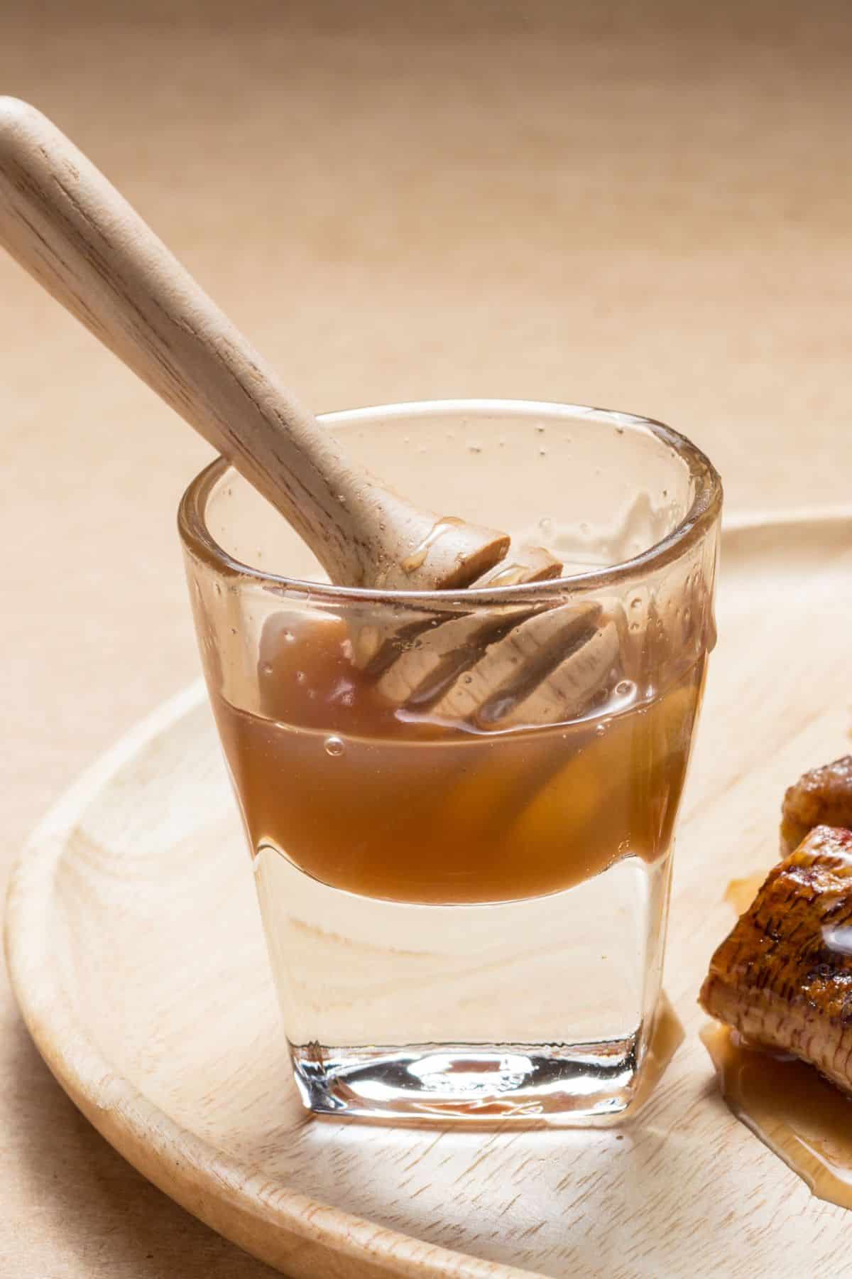 Clear glass container with coconut nectar on wooden surface.
