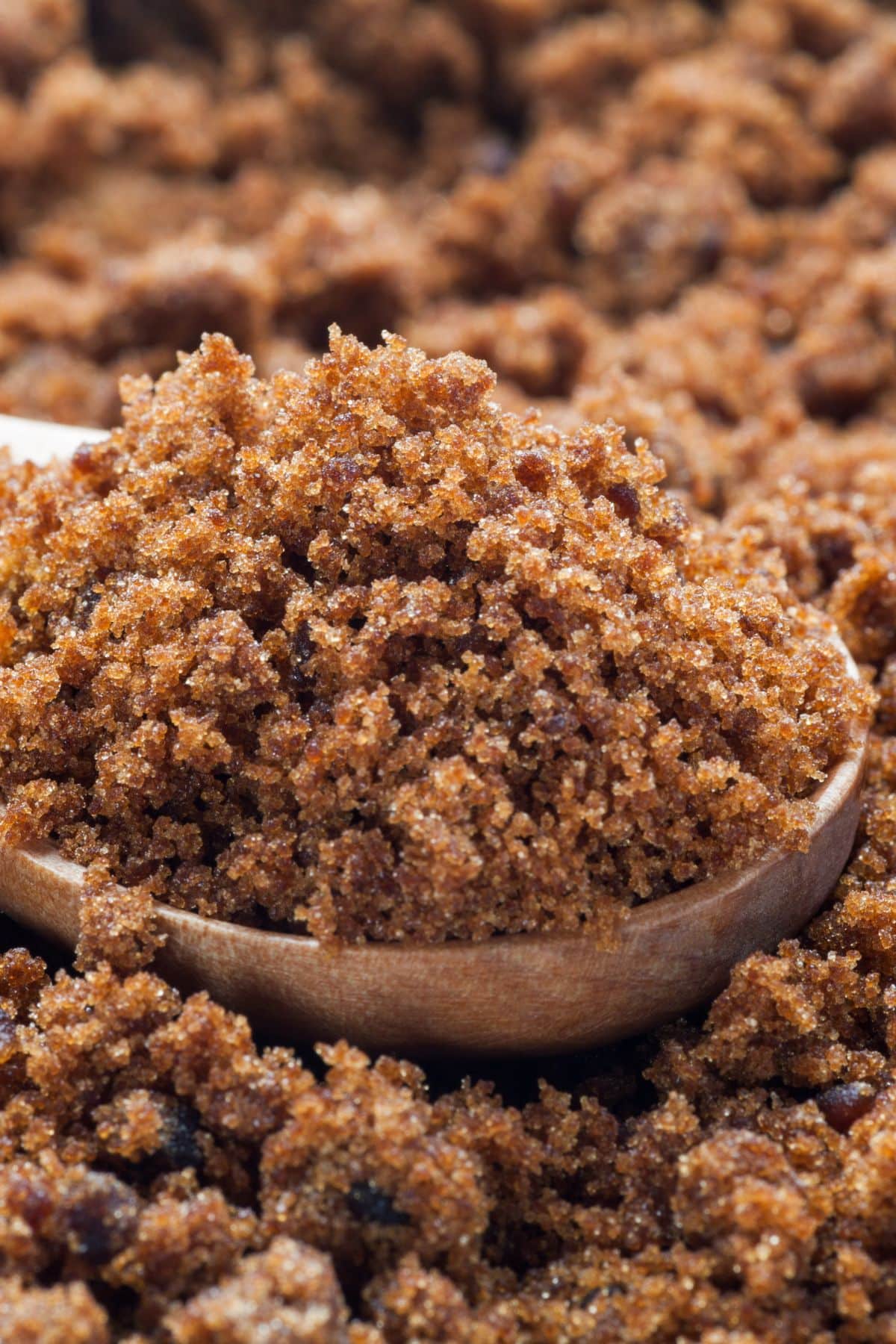 Ground date sugar on wooden spoon and table surface.