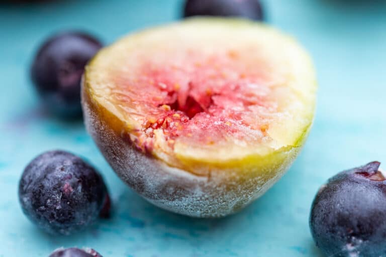 Closeup of a frozen half fig with blueberries on a counter.