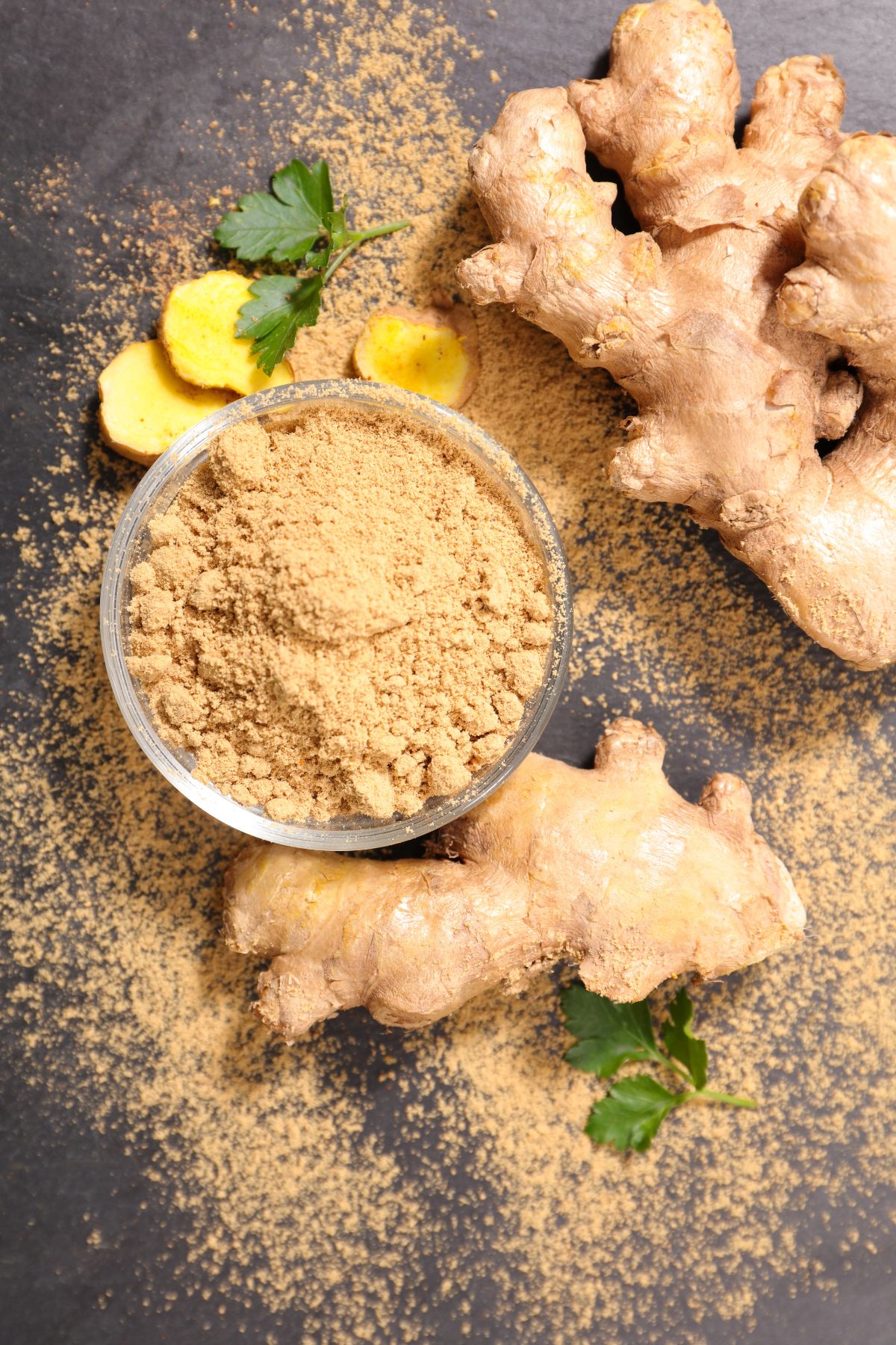 Bowl of ginger powder with raw ginger root.