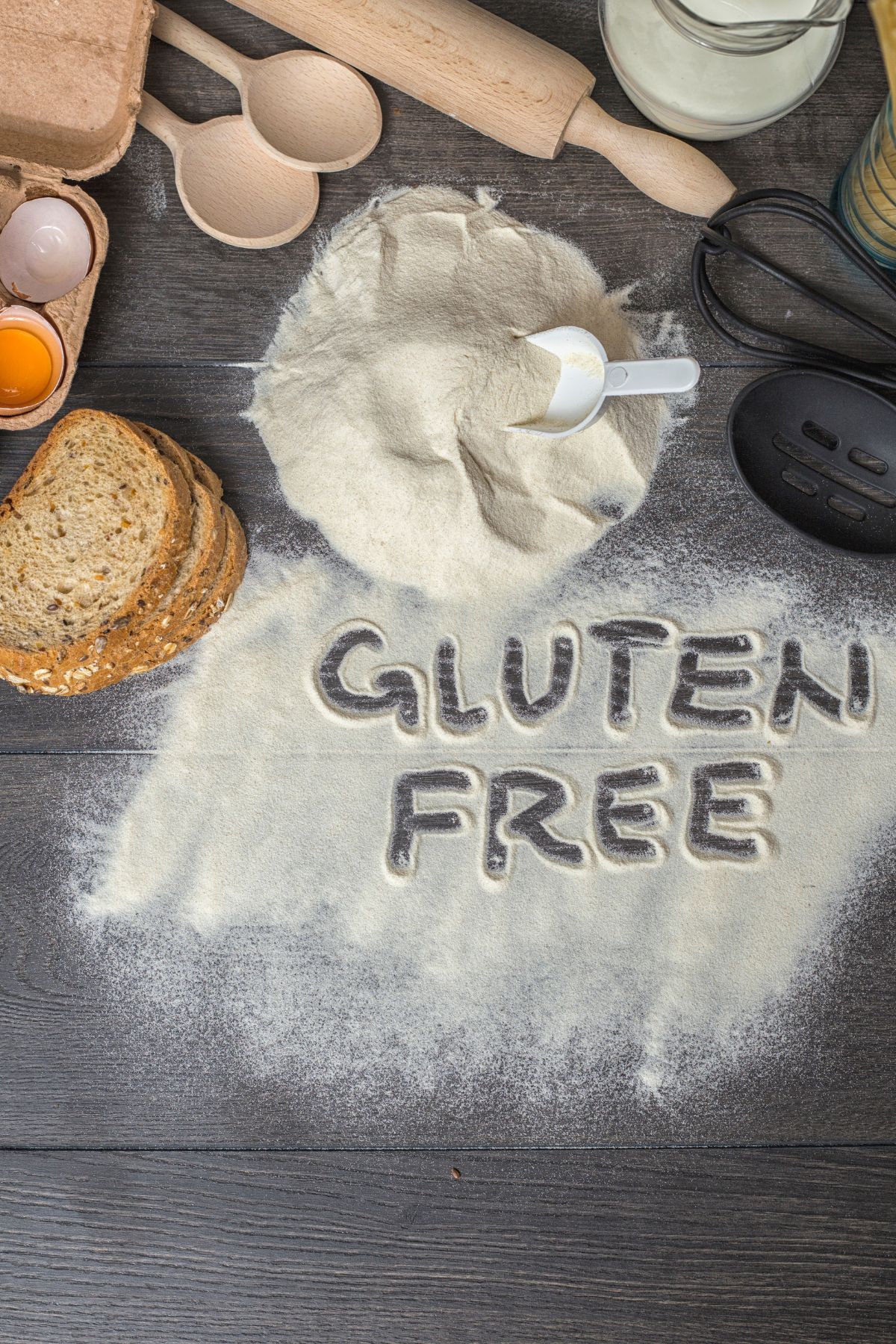 Gluten free flour with baking utensils on dark wooden surface.