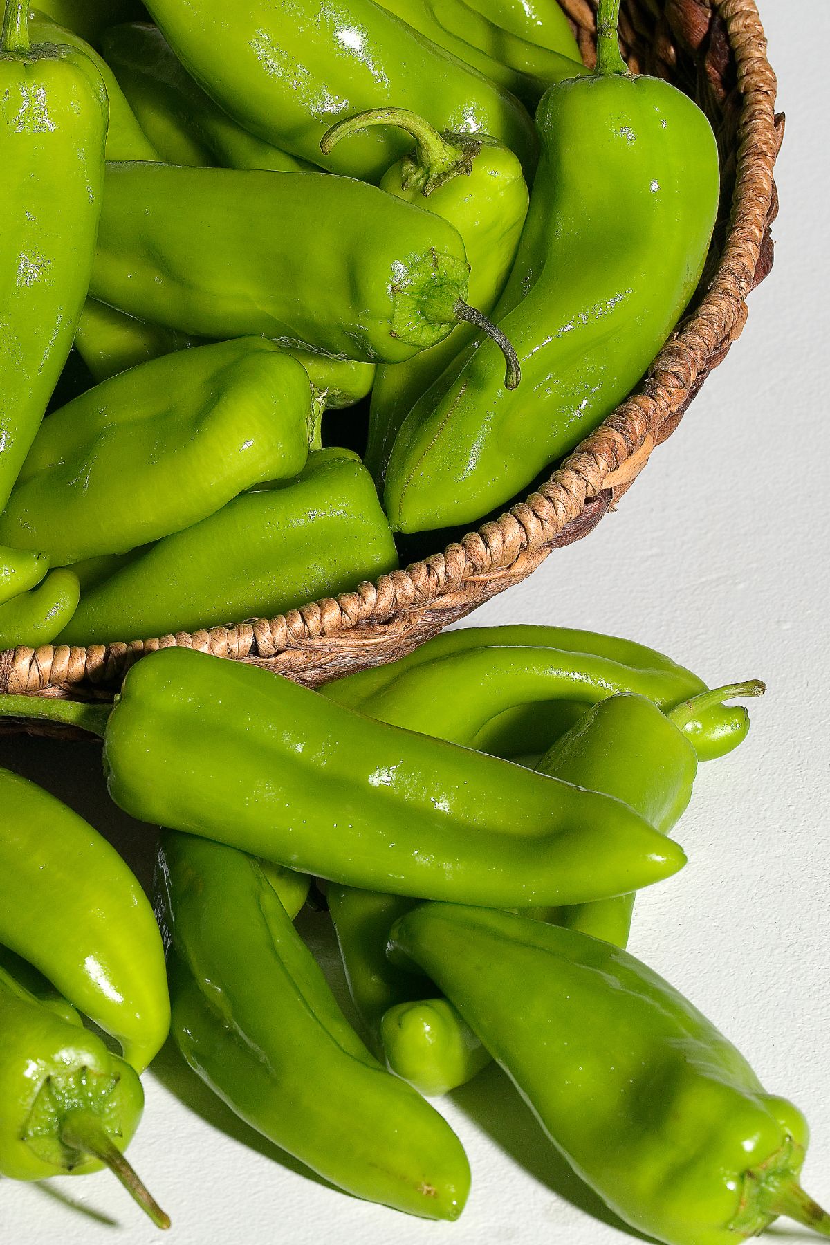 Basket of green chilis on tabletop.