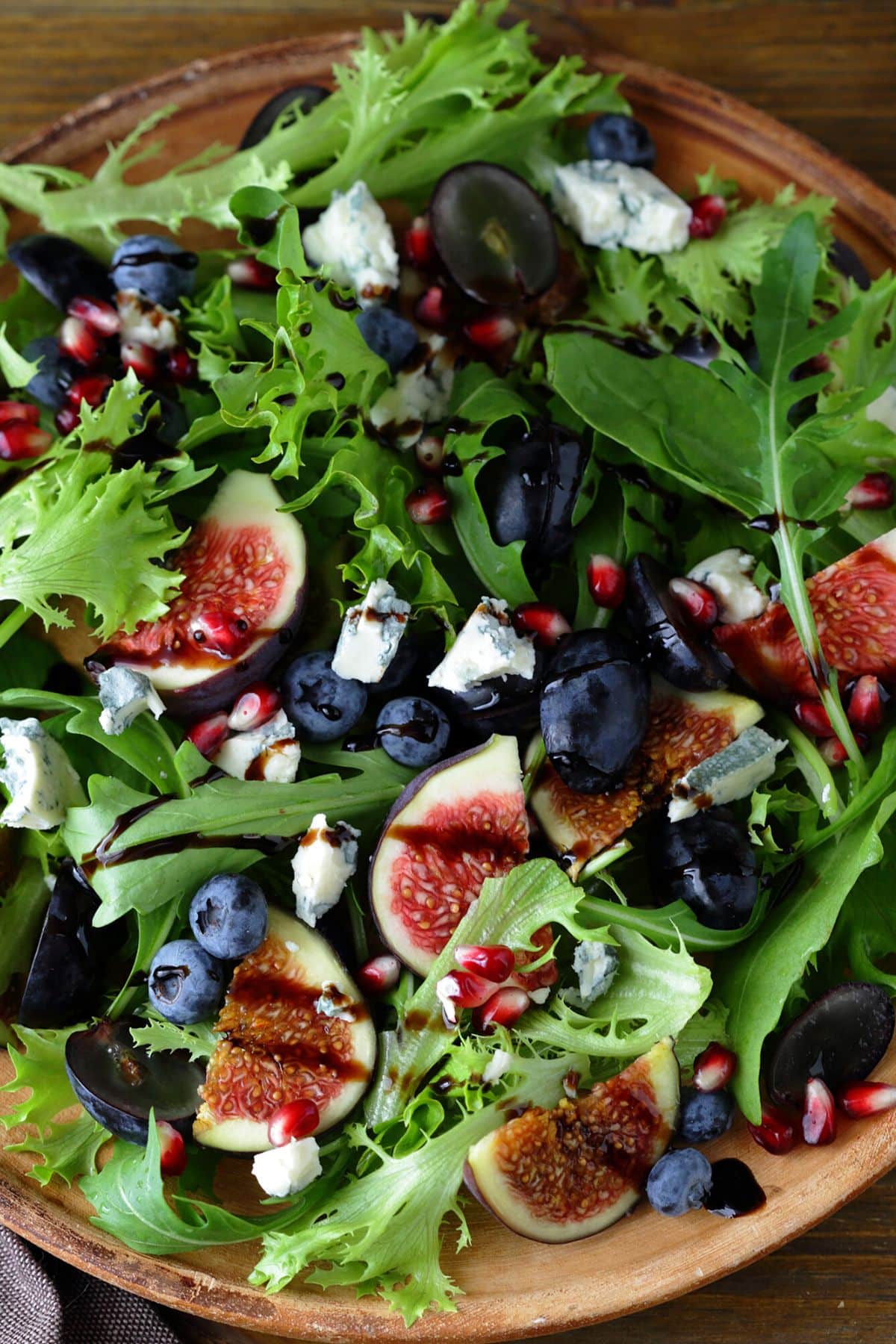 A leafy green salad with figs and blueberries and a balsamic drizzle.