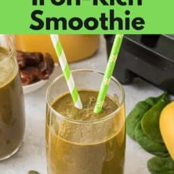 A glass of iron rich green smoothie with two green striped straws.