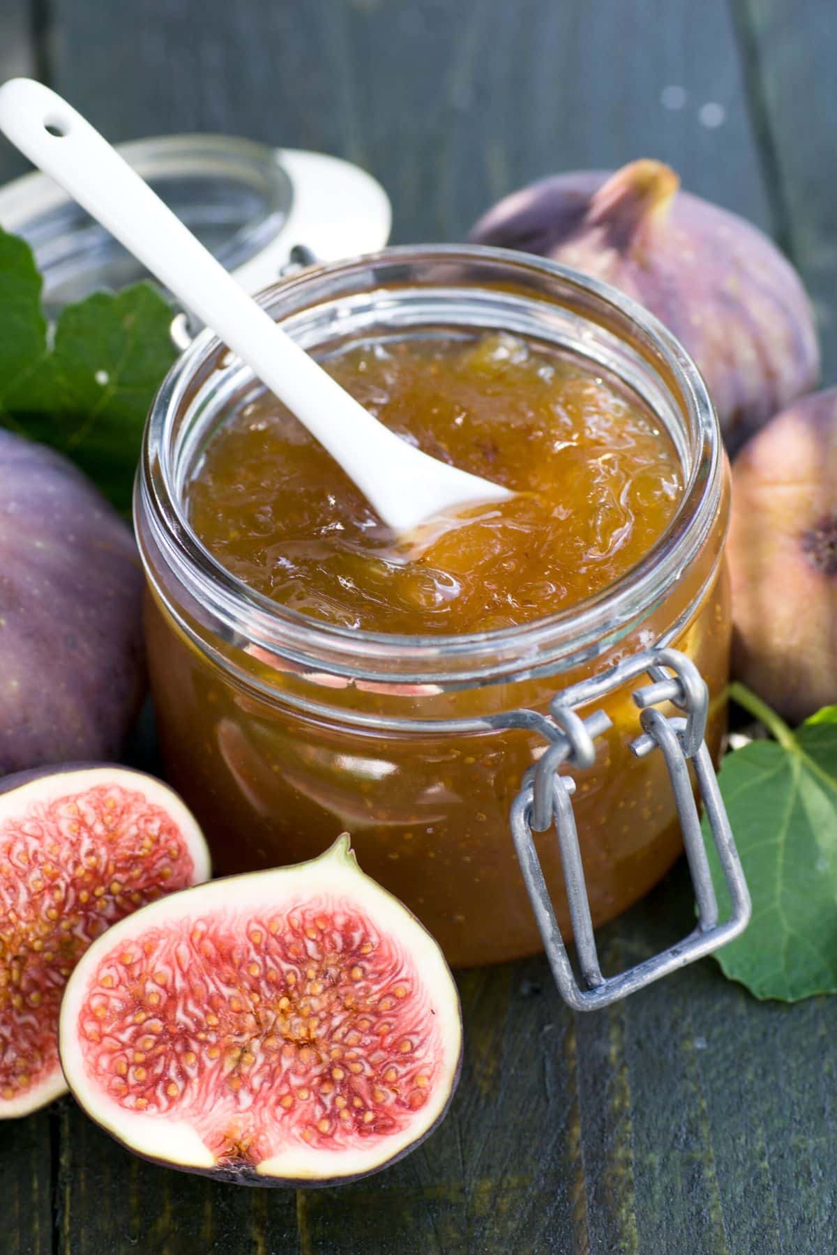 A flip top jar filled with fig jam and a white spoon.