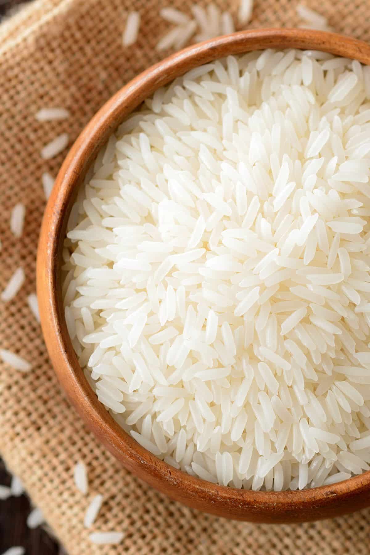 Bowl of jasmine rice on burlap surface.