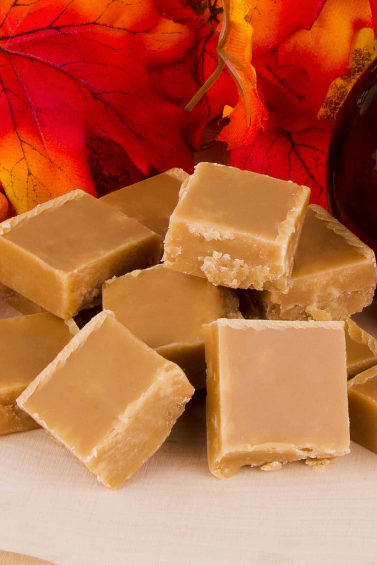 Blocks of maple sugar on wooden surface with fall leaves.