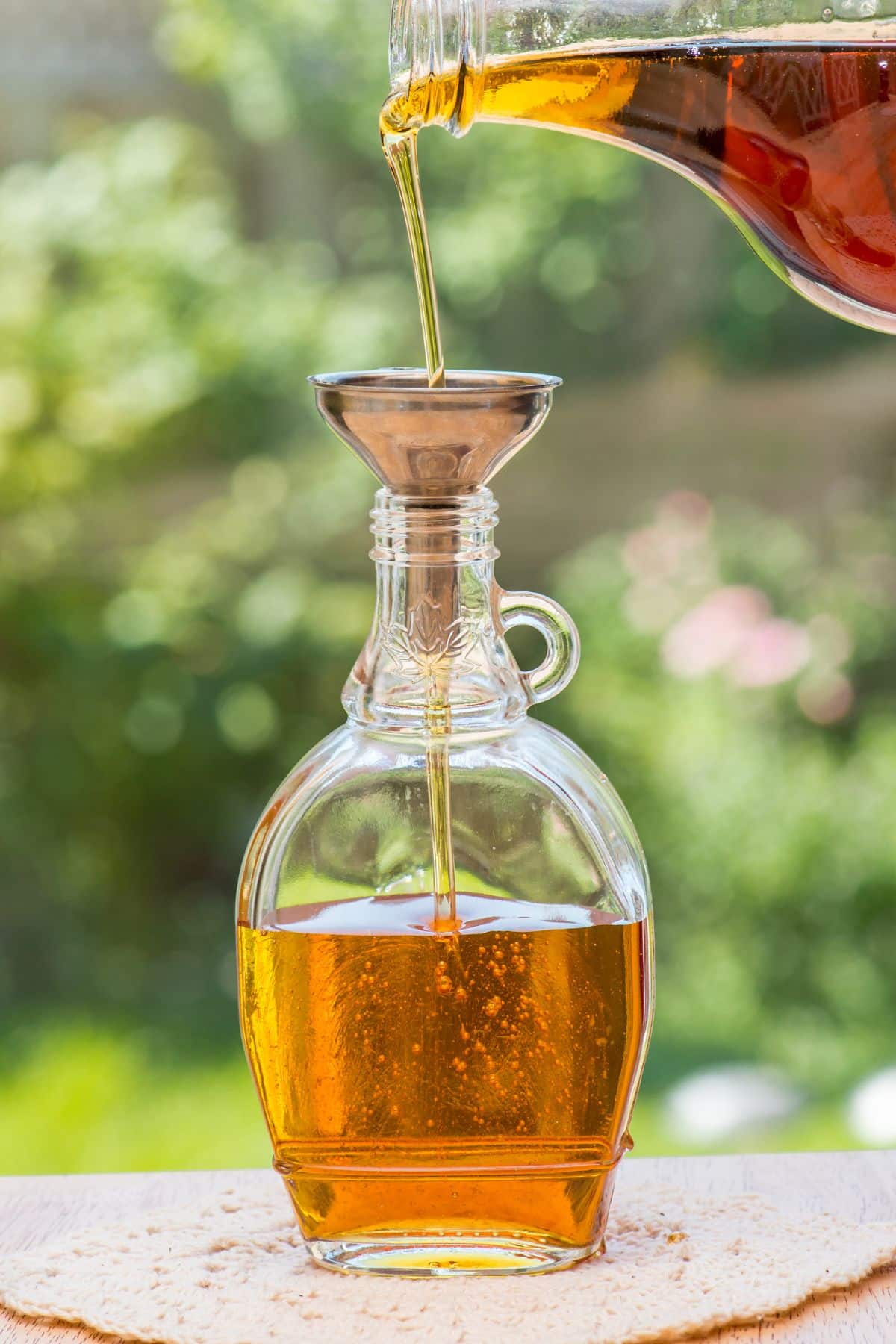 Maple syrup pouring into funnel filling a jar.