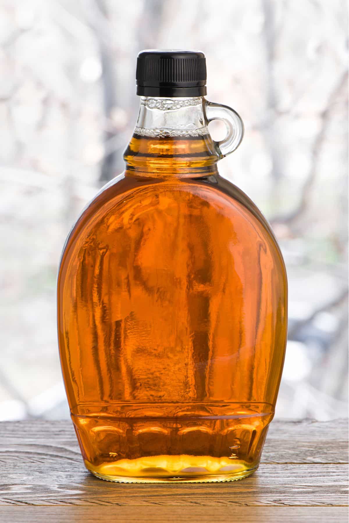 Jar of maple syrup on wooden surface.
