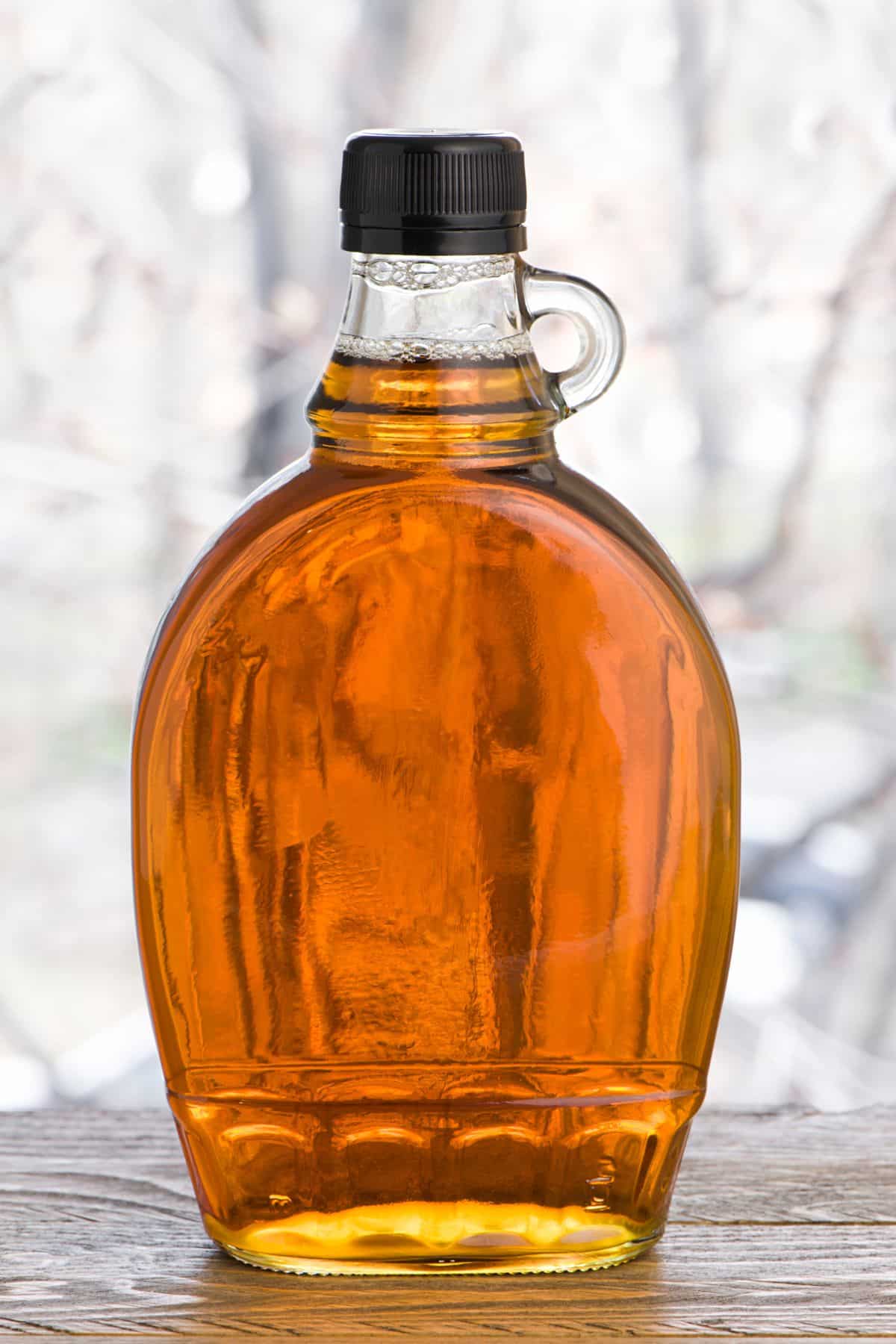 Bottle of maple syrup on wooden surface.