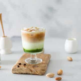 A layered matcha green tea iced espresso on a wooden board.