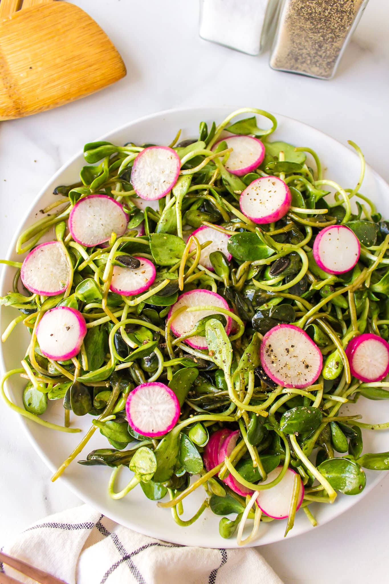 Microgreens with radish salad on a white plate.