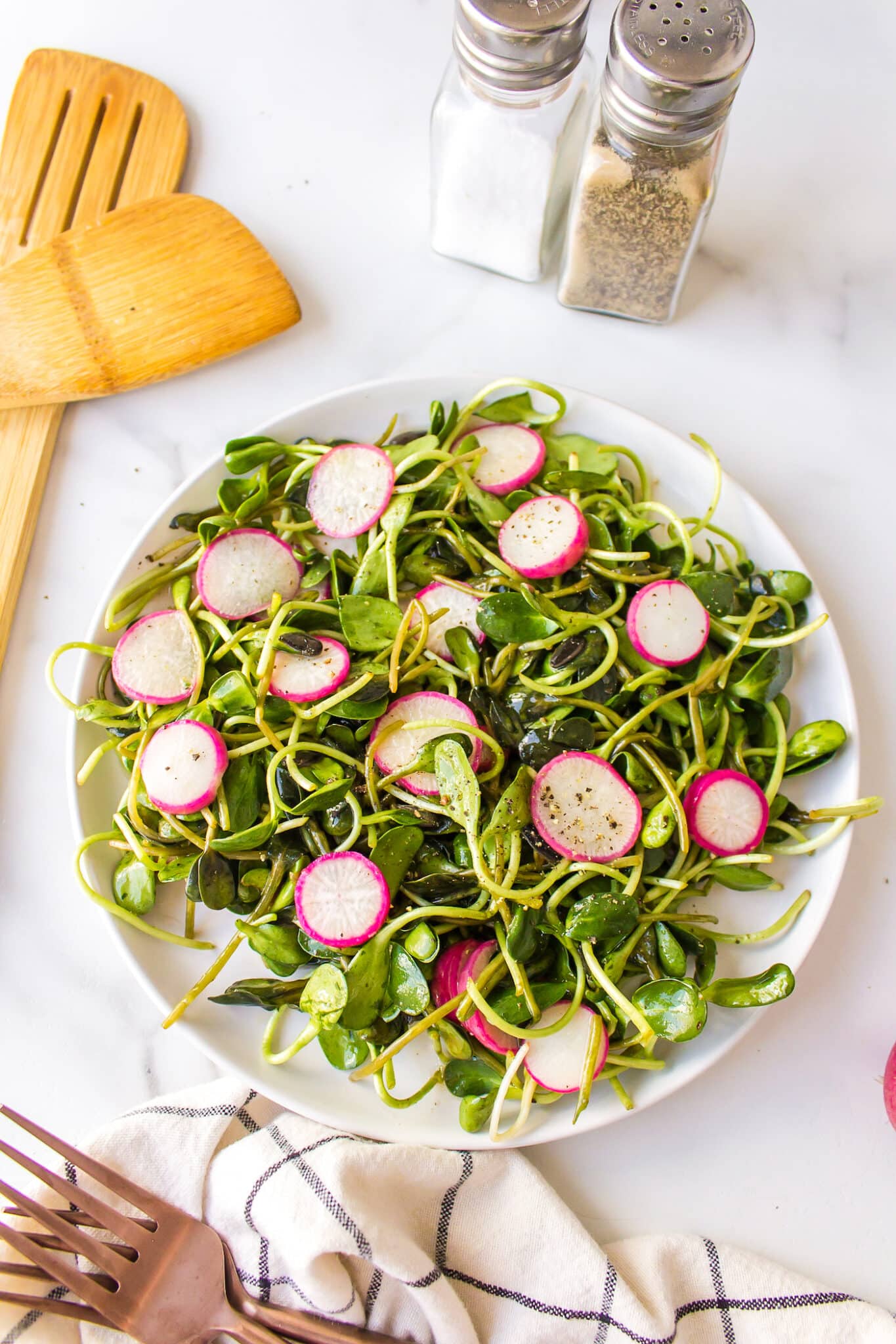 Microgreens with radish salad on a white plate.