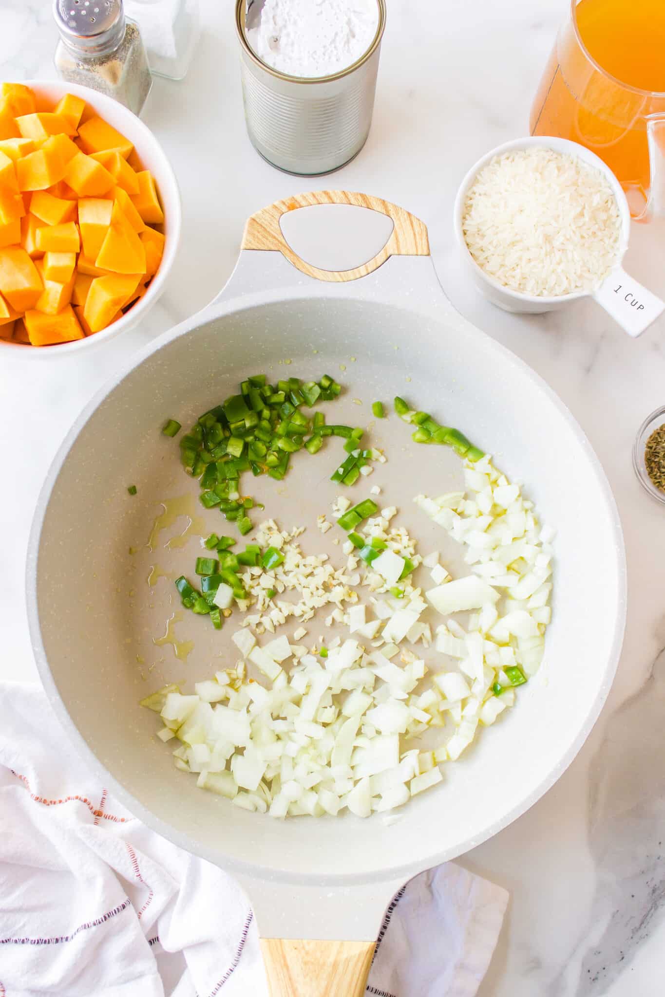 Diced onions and garlic in a white saucepan.