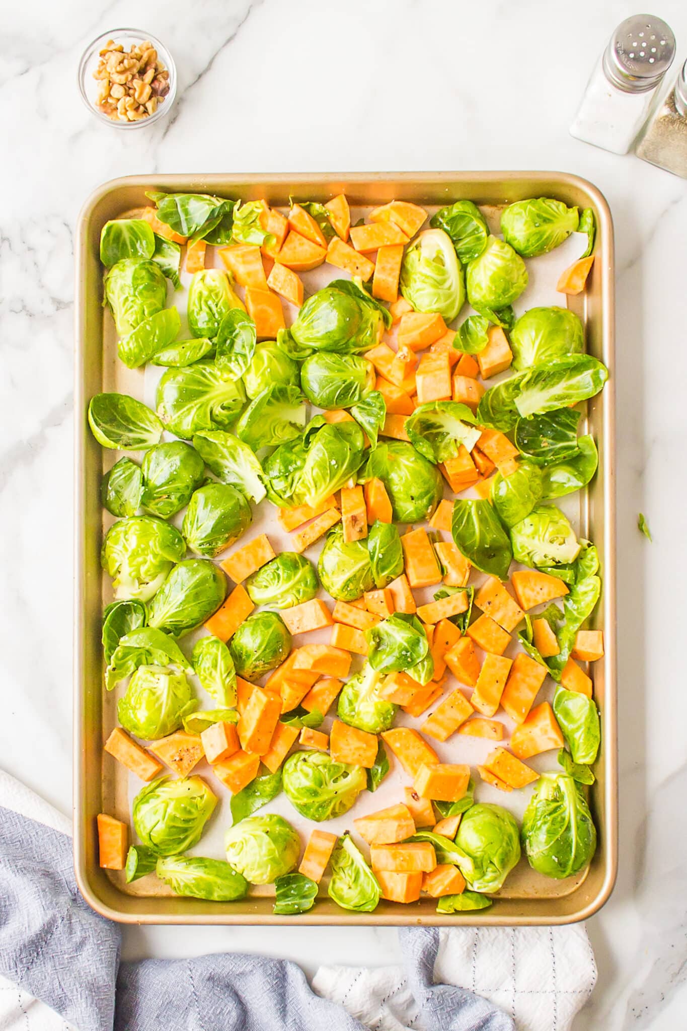 Sweet potatoes and Brussels sprouts on a parchment lined baking sheet.