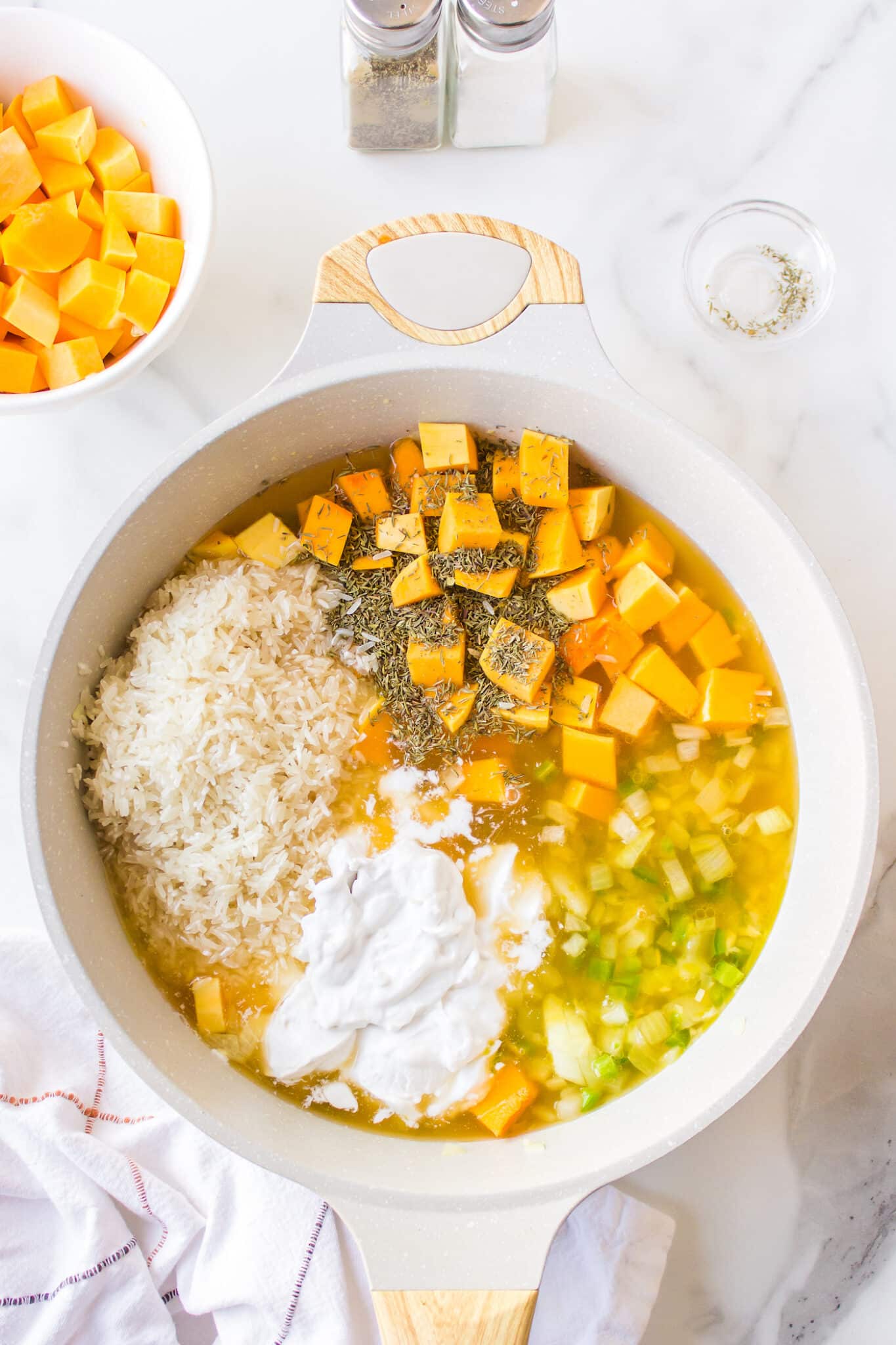 Ingredients to make pumpkin rice in a white saucepan.