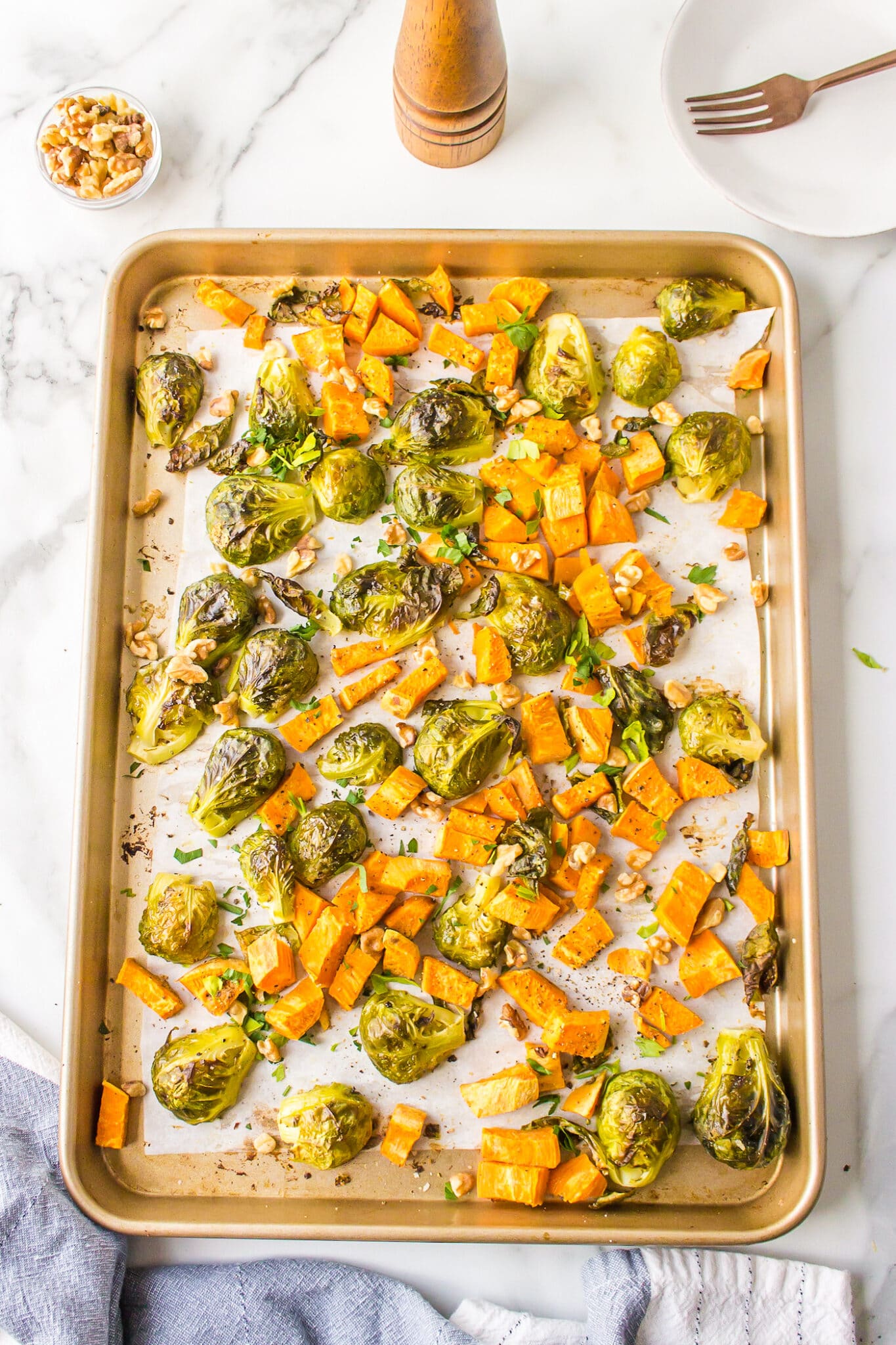 Roasted brussels sprouts and sweet potatoes on a baking sheet.