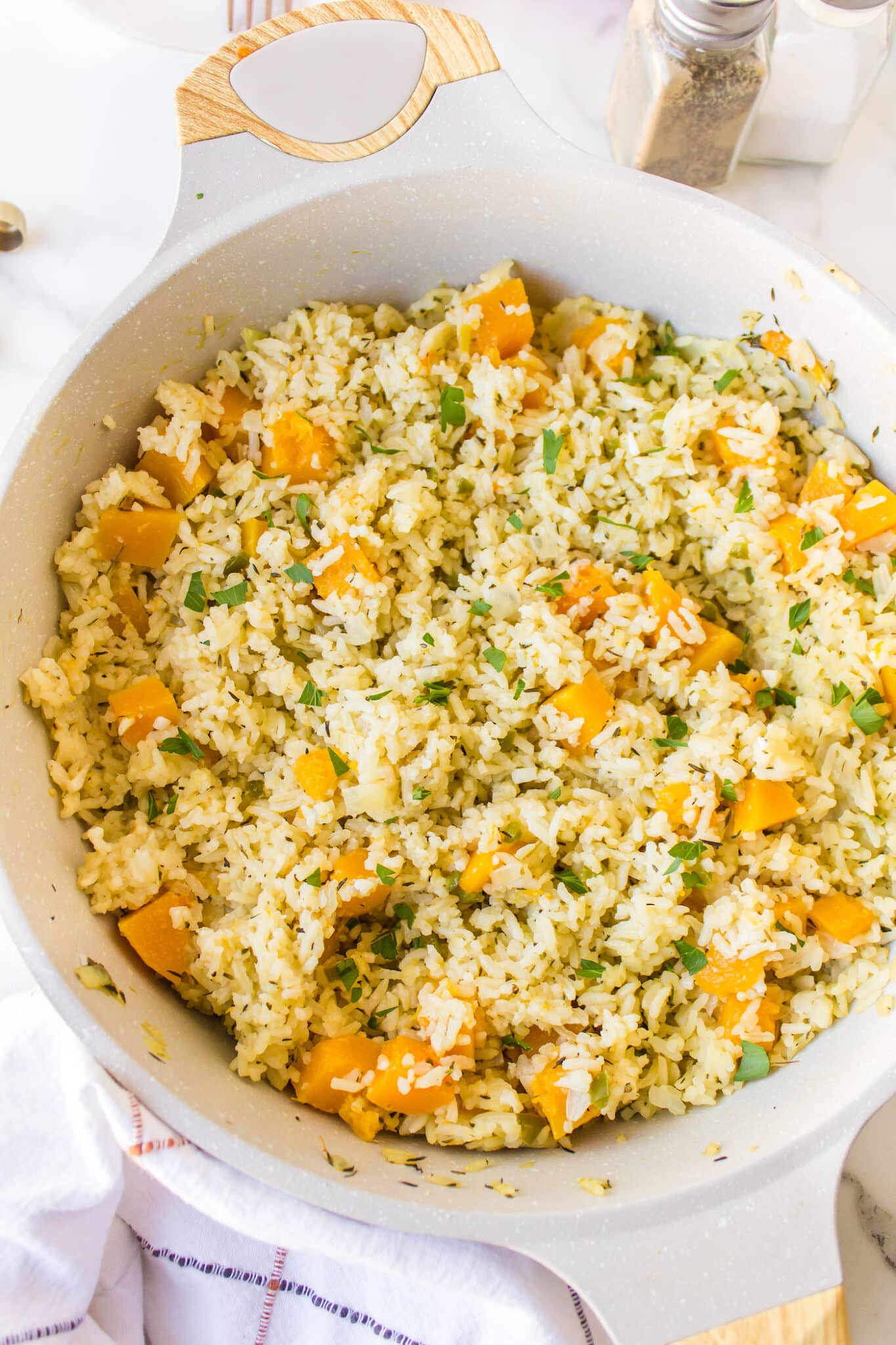 A white stockpot filled with cooked pumpkin rice.