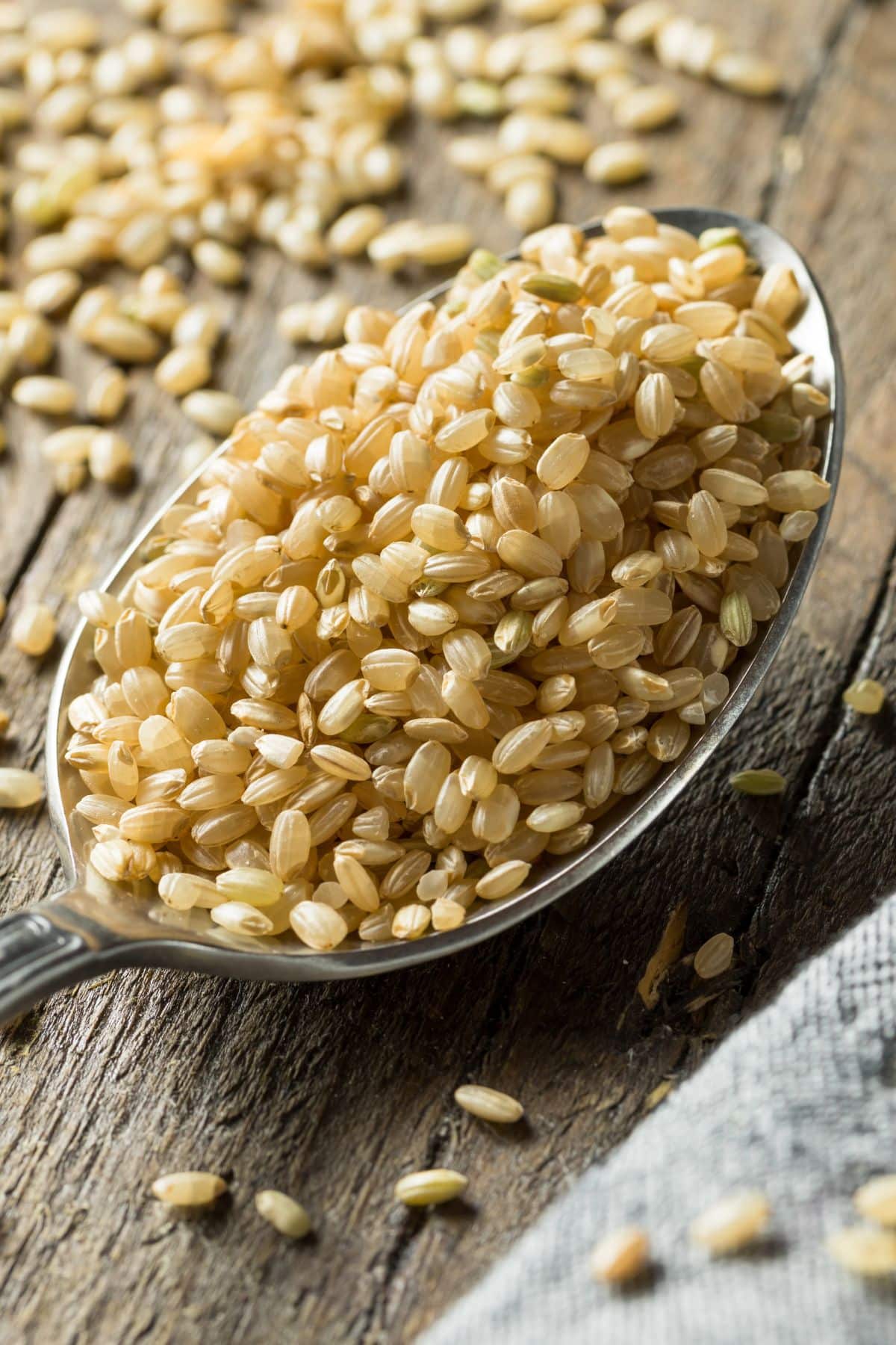 Spoonful of short grain brown rice on wooden surface.