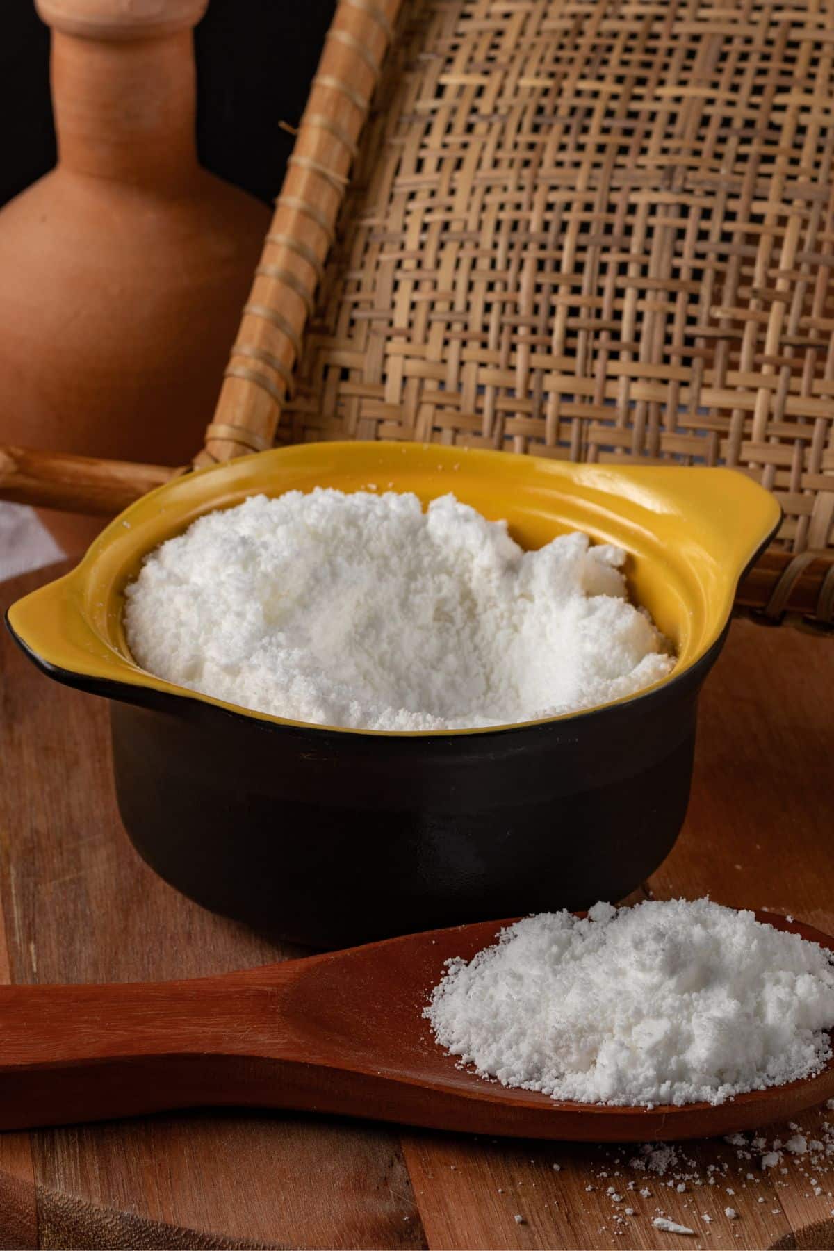 Bowl and spoonful of tapioca flour on wooden surface.