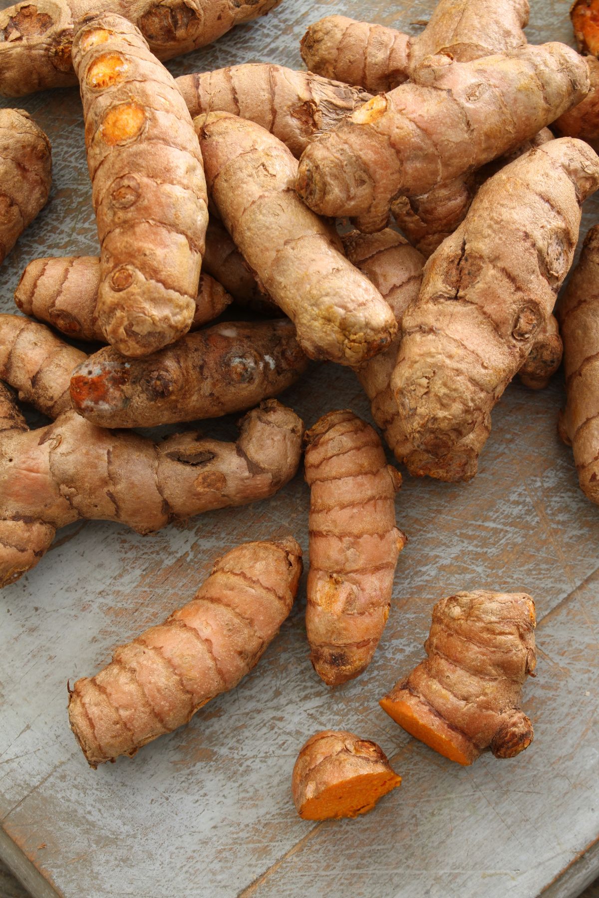 Raw turmeric root on wooden surface.