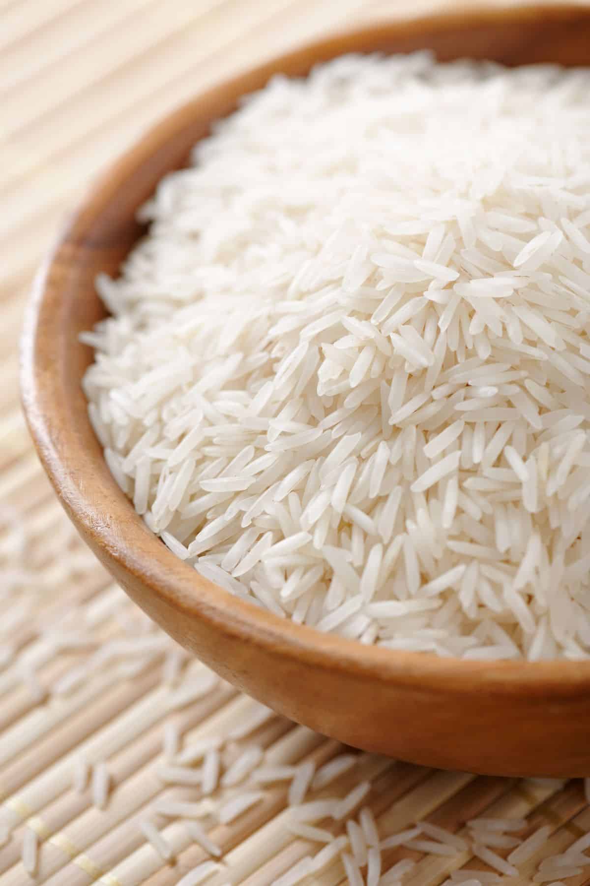 Bowl of white basmati rice on bamboo mat.