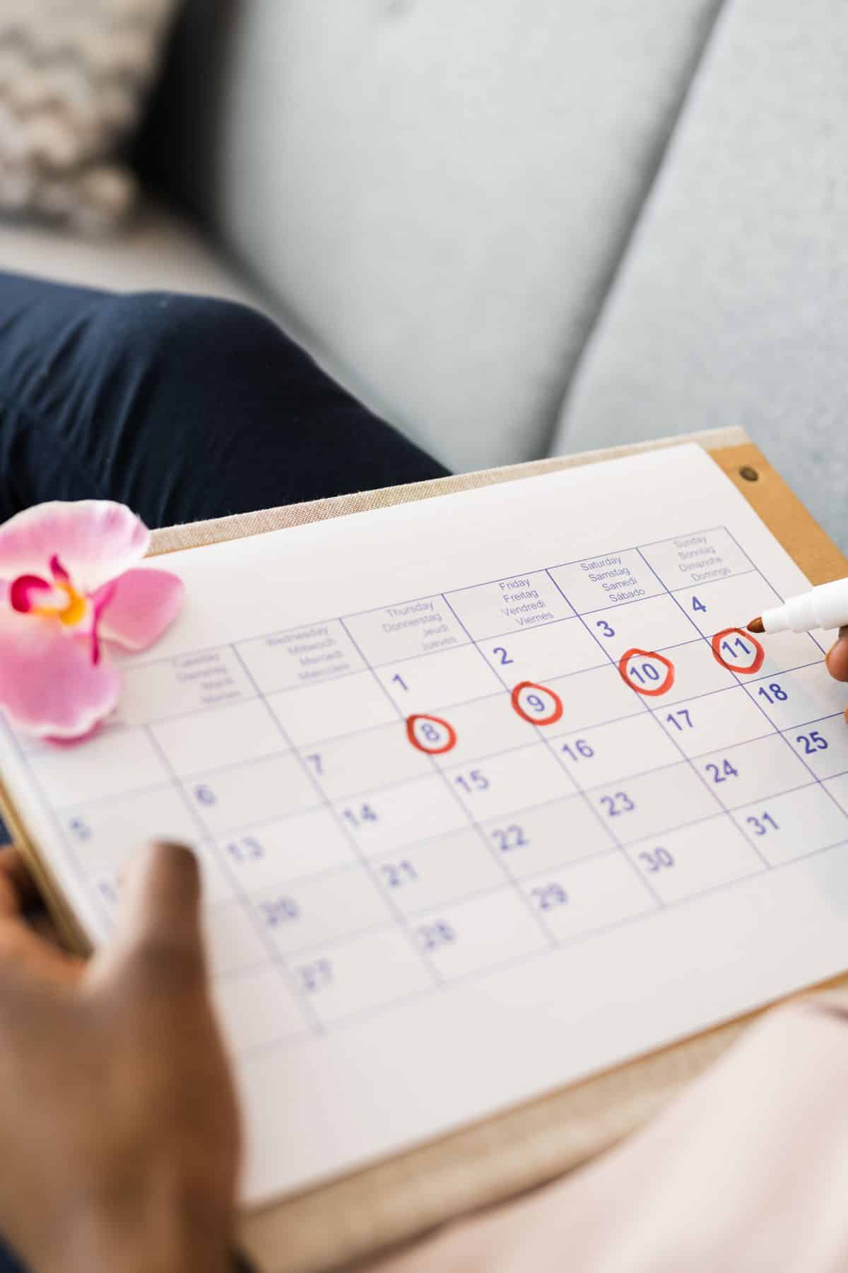 woman checking off a calendar for her menstrual cycle. 