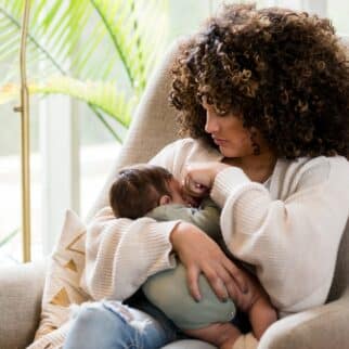 Black woman in an armchair breastfeeding her infant.