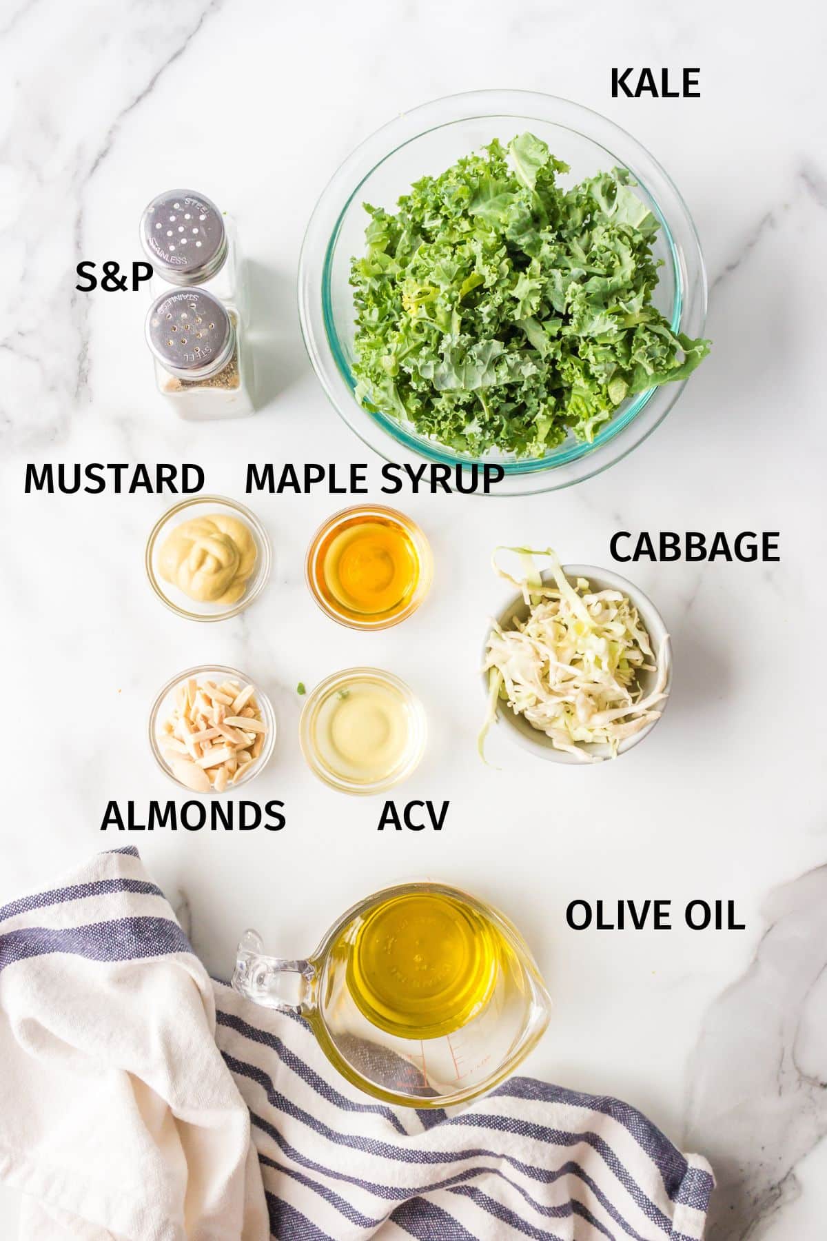 Ingredients to make CFA Kale Salad in bowls on a white surface.