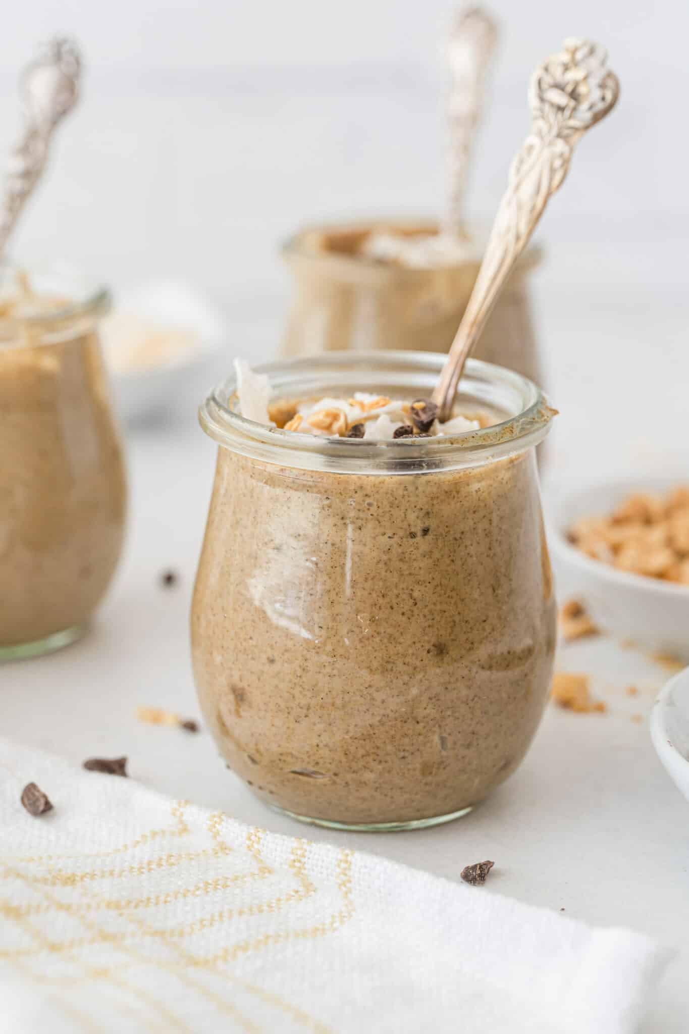 Small jars of peanut butter chia pudding topped with chocolate and coconut.