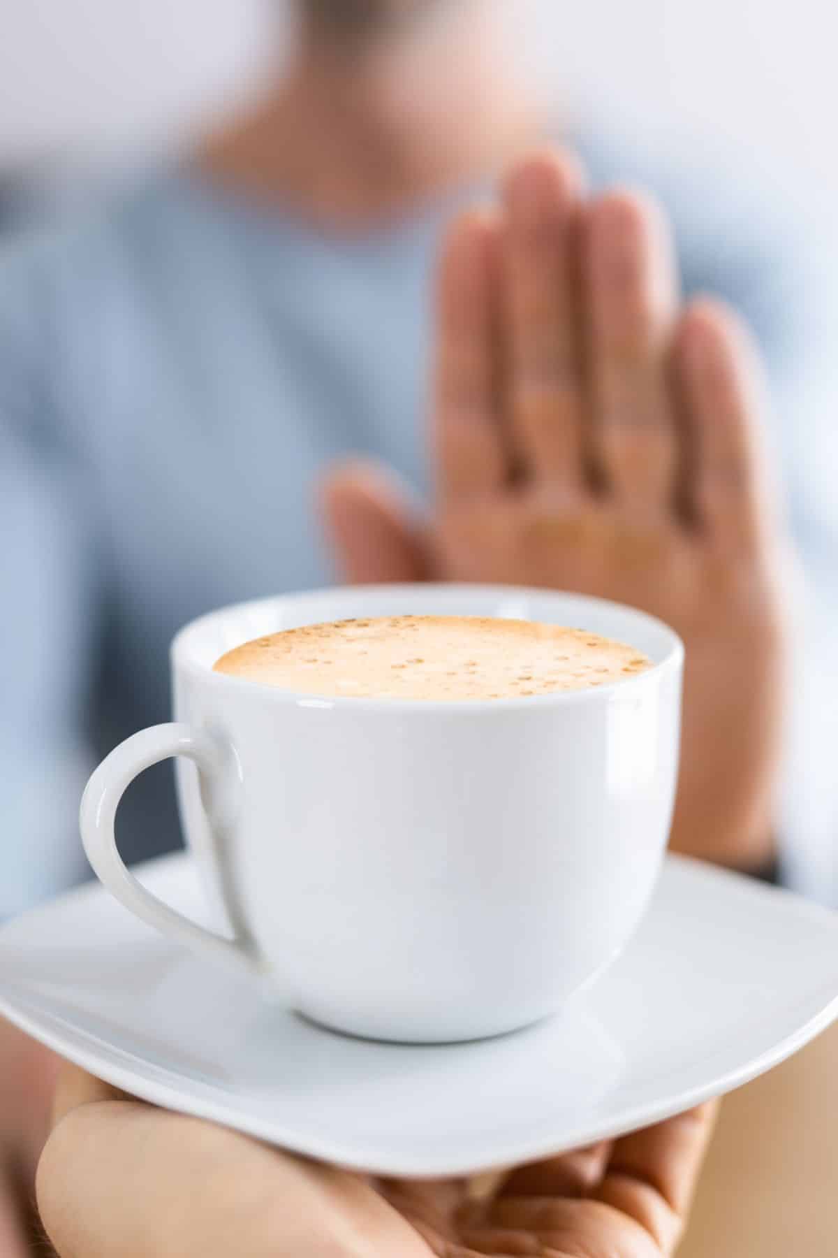 woman pushing away a mug of coffee.