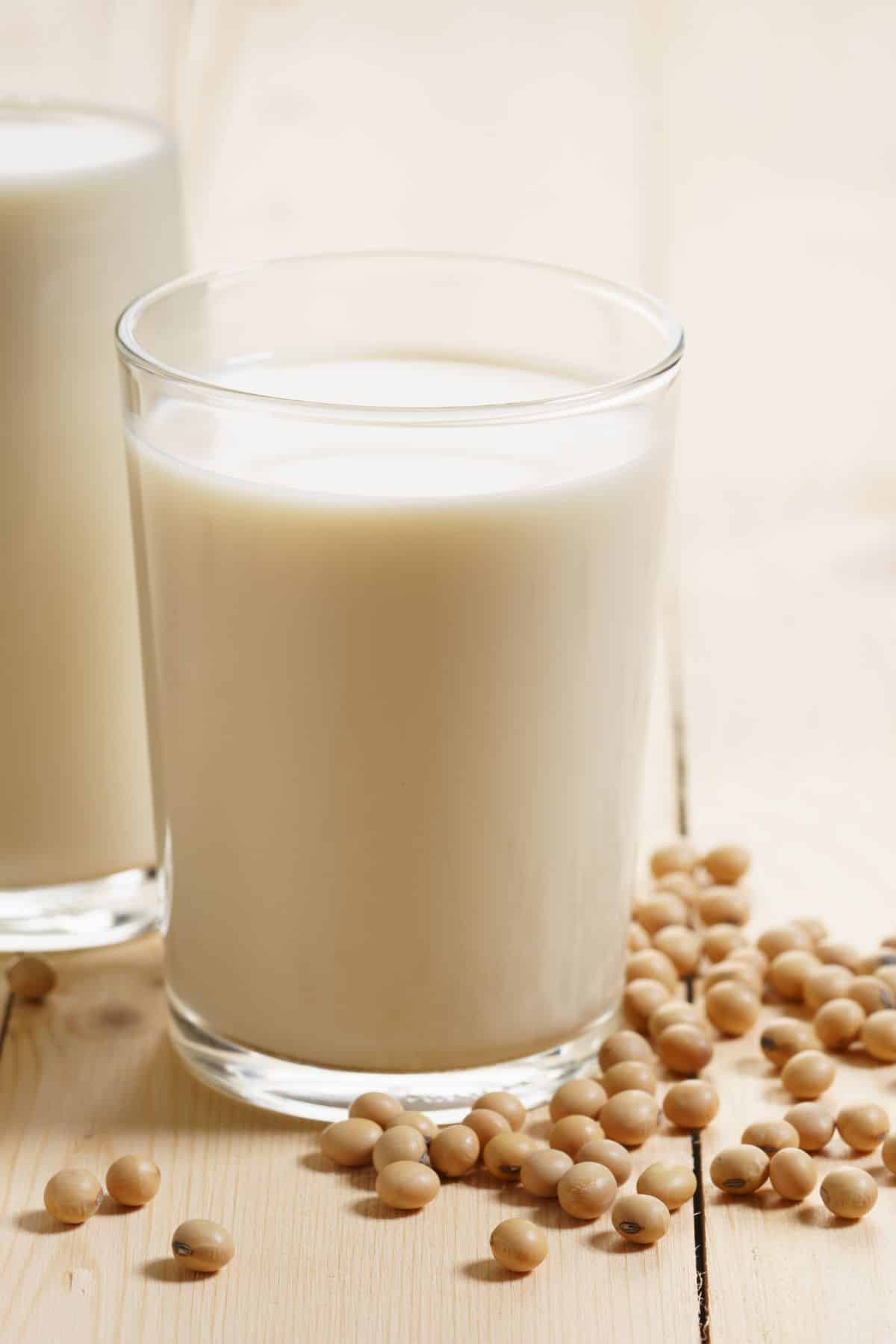 a cup of soy milk surrounded by soy beans.