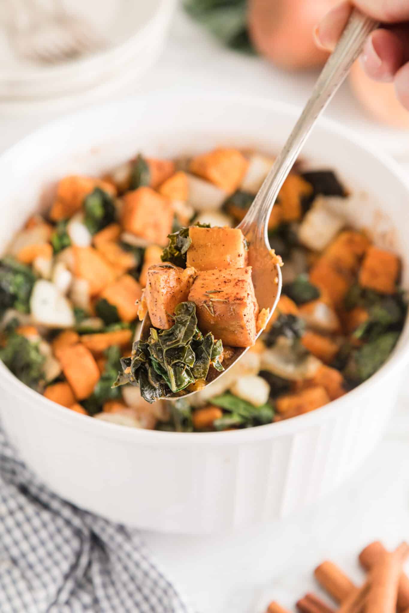 A forkful of sweet potato and kale over the serving bowl.