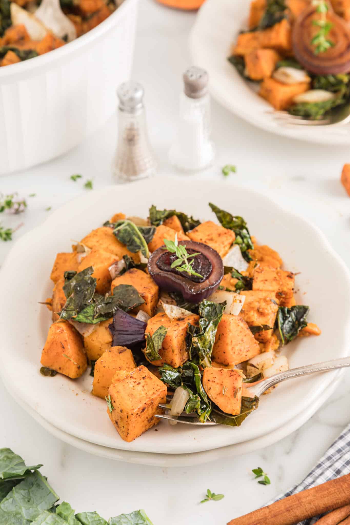 plate of baked sweet potato, kale and onion with fork.