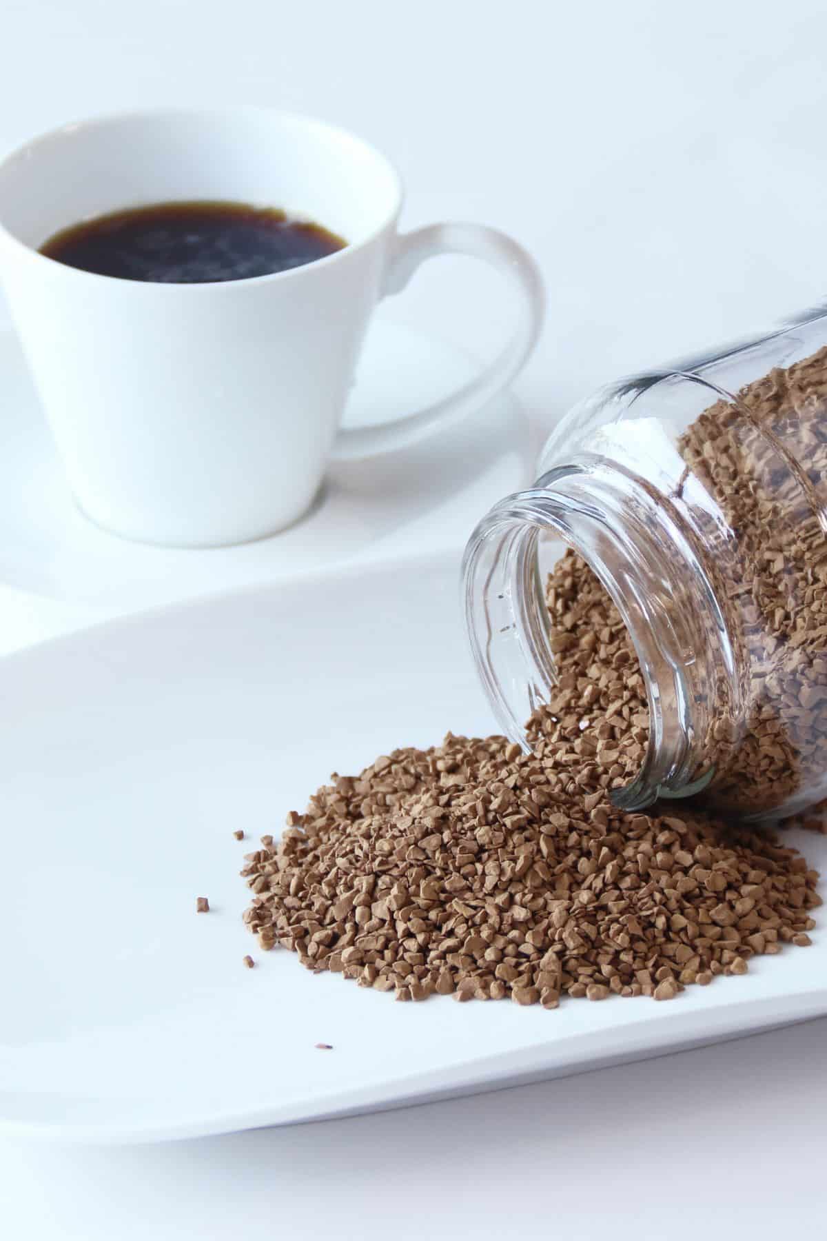 a jar of instant decaf coffee pouring out onto a white plate.