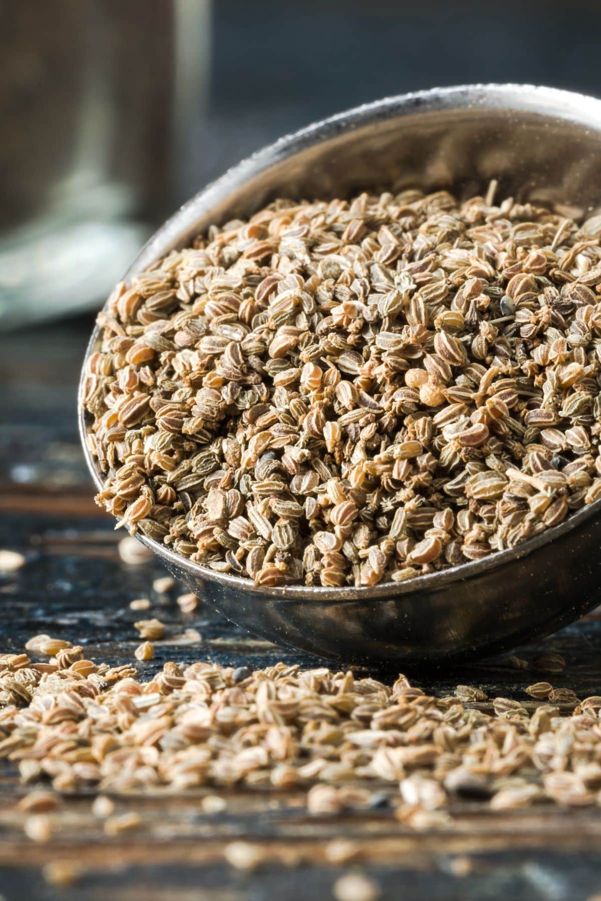 Bowl of celery seed spilling onto wooden surface.