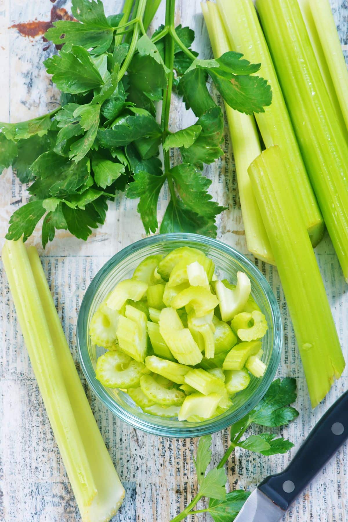 Sliced and chopped bowl of celery on white surface.