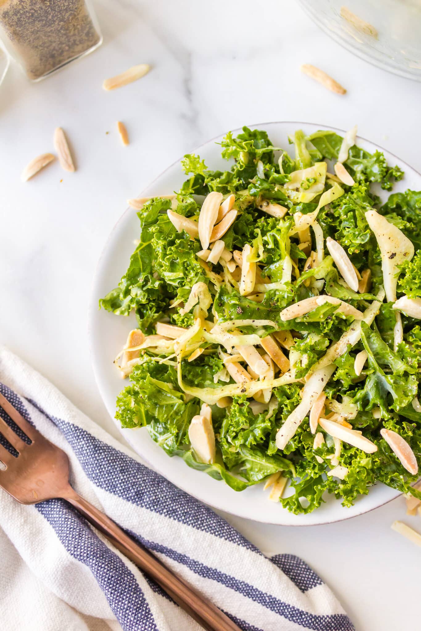 A small white bowl of CFA Copycat Kale Salad with almonds.