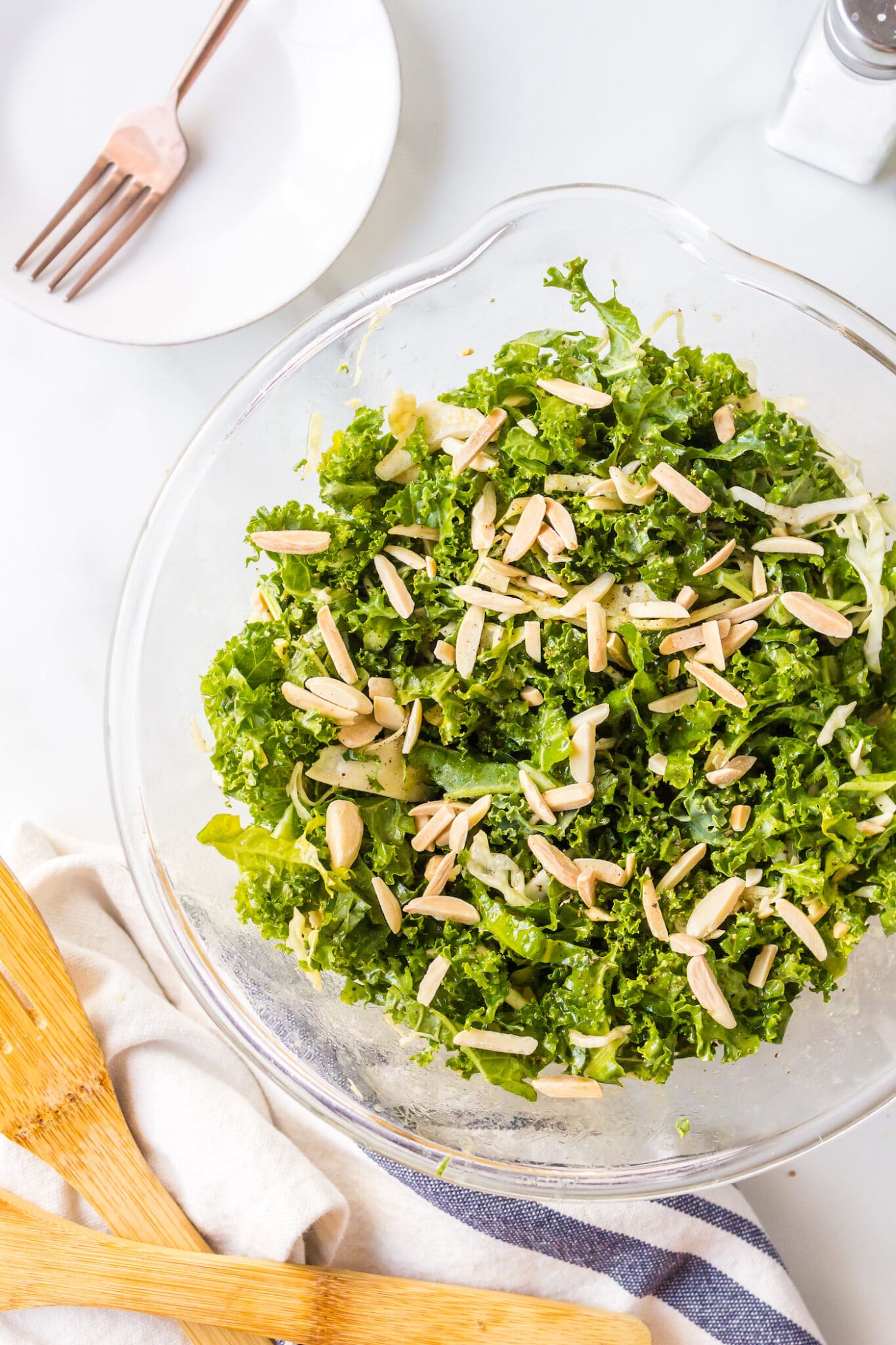 Chopped kale salad topped with slivered almonds in a glass bowl.