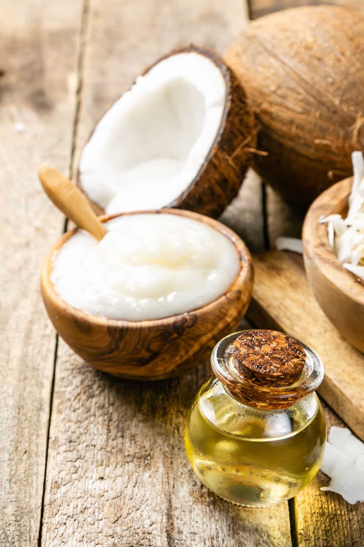 Bowl of coconut butter and coconut oil on wooden surface.