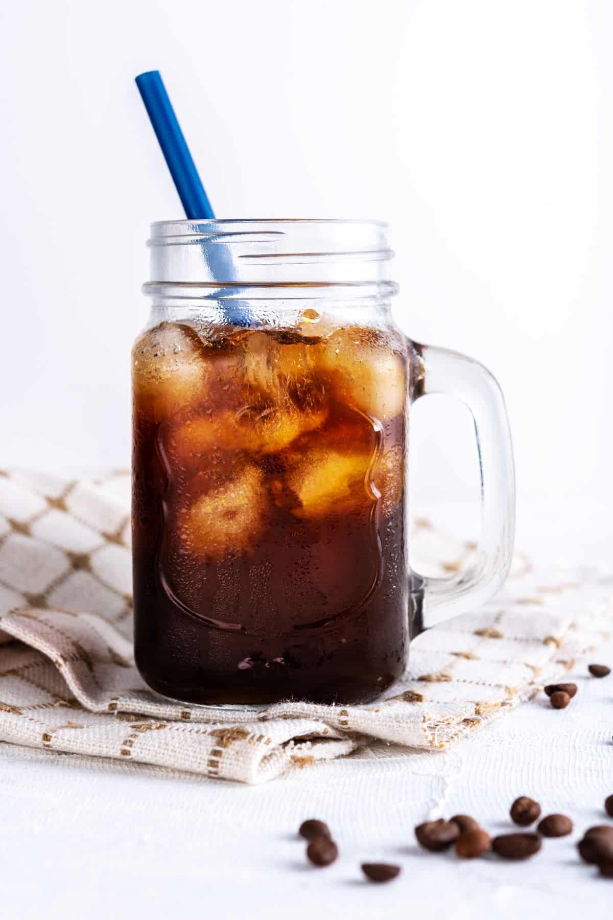 a glass of cold-brew coffee with a blue straw.