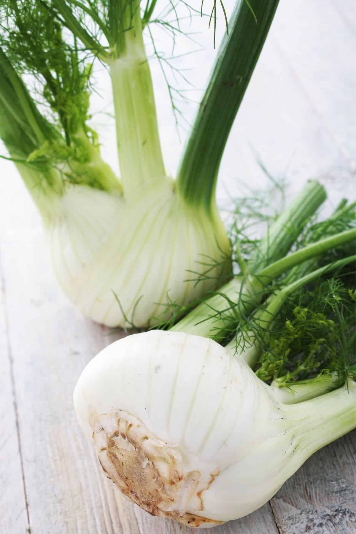 Whole fennel bulbs on wooden surface.